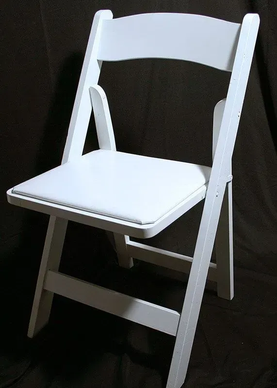 A white folding chair with a padded seat, shown against a dark, neutral background.