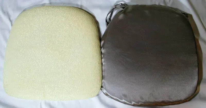 A foam chair cushion insert placed next to its gray fabric cover on a white surface.