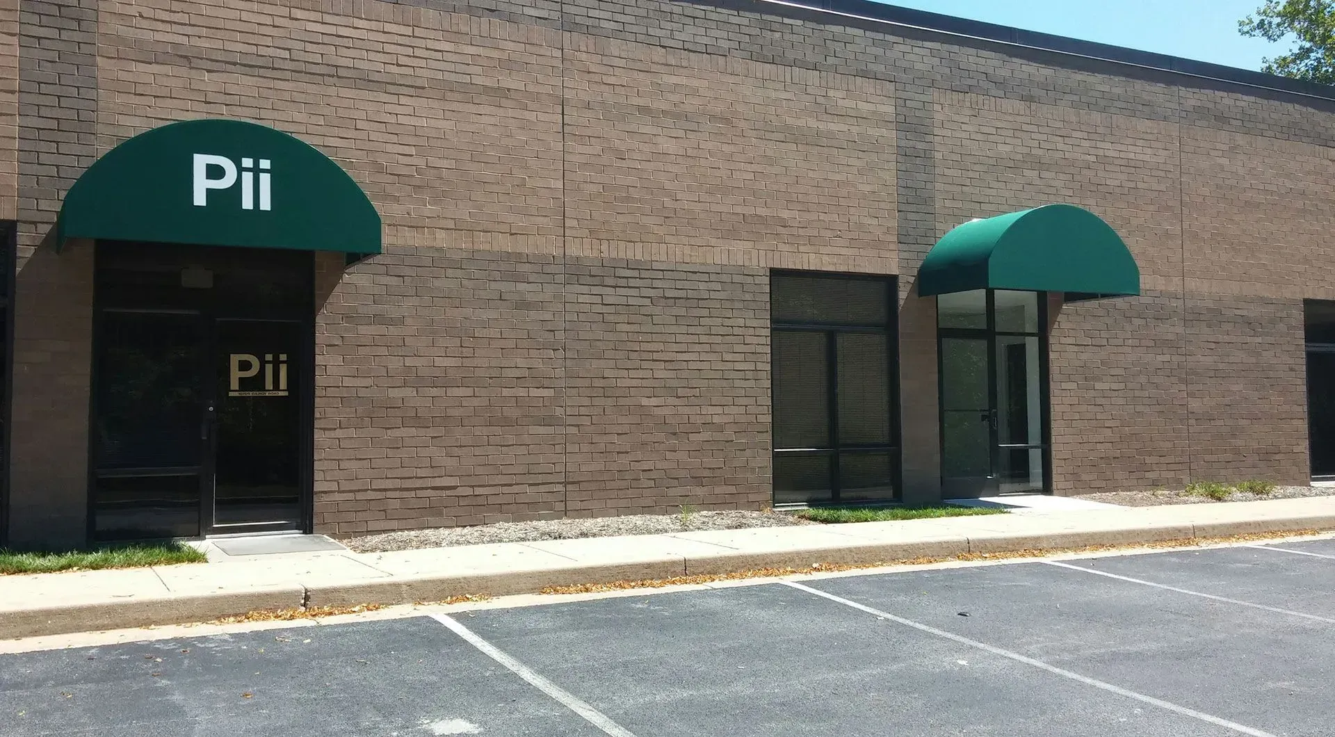 A brick commercial building with two entrances marked by green awnings, one labeled with the sign 