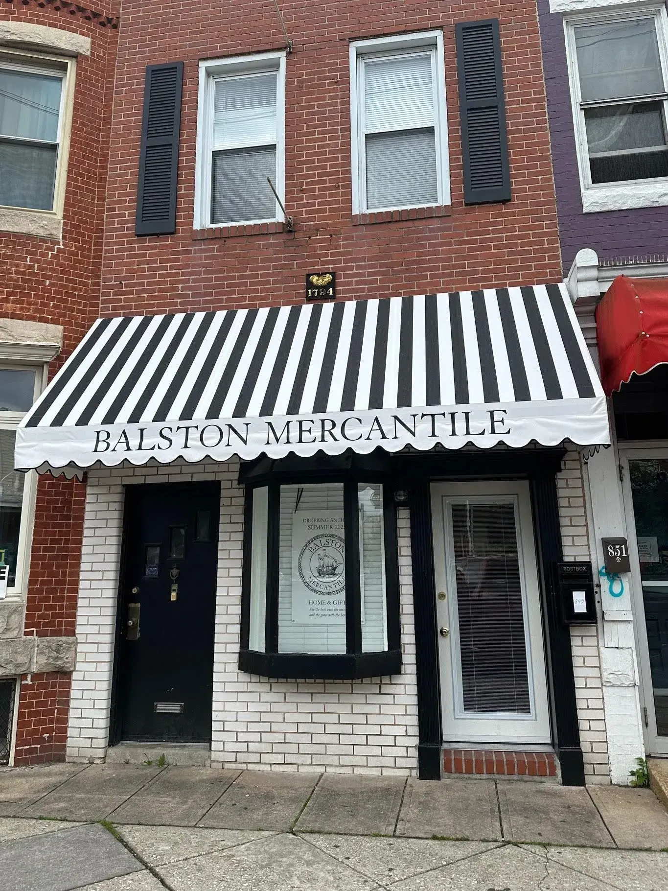 A brick building storefront with a black-and-white striped awning labeled 