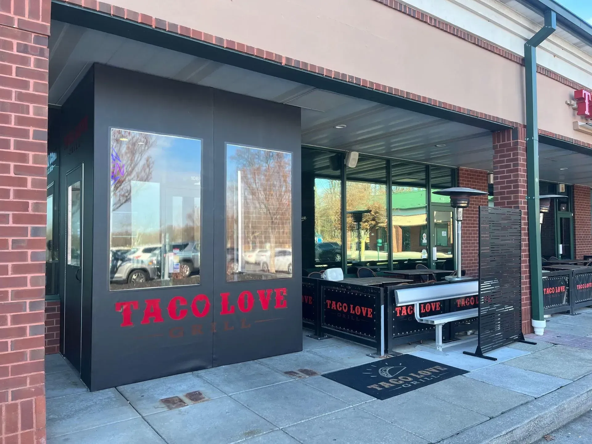Exterior of Taco Love restaurant with a dark covered patio and red signage on a brick building.