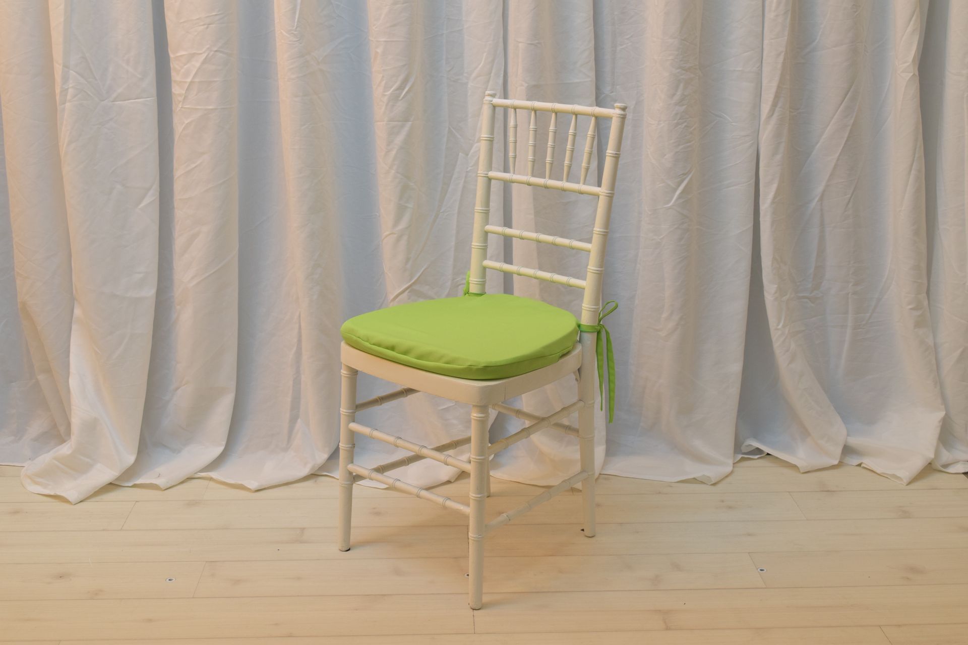 White chair with a bright green cushion on a wooden floor
