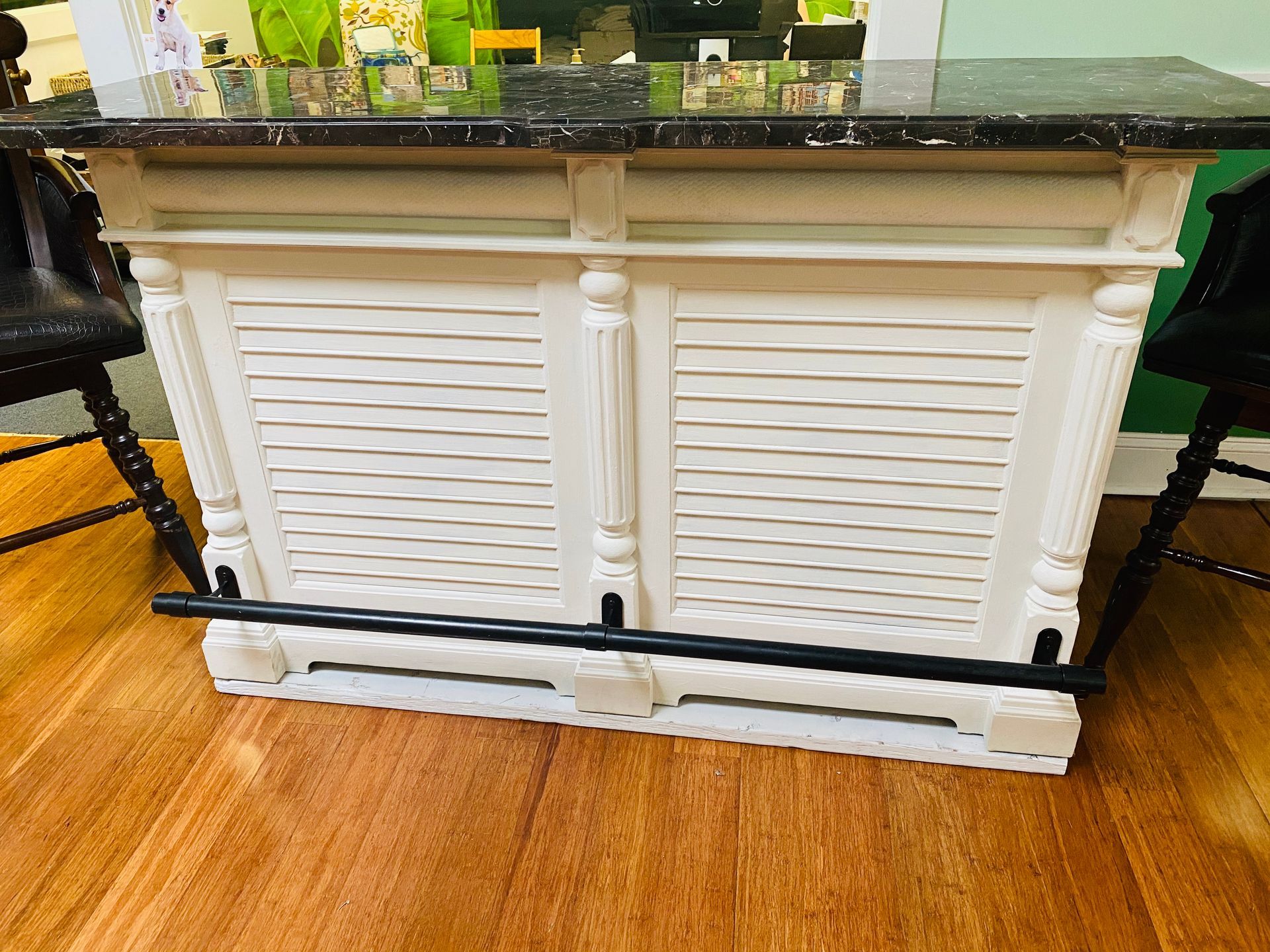 White louvered cabinet/bar counter in a room with a black granite top and wooden floor