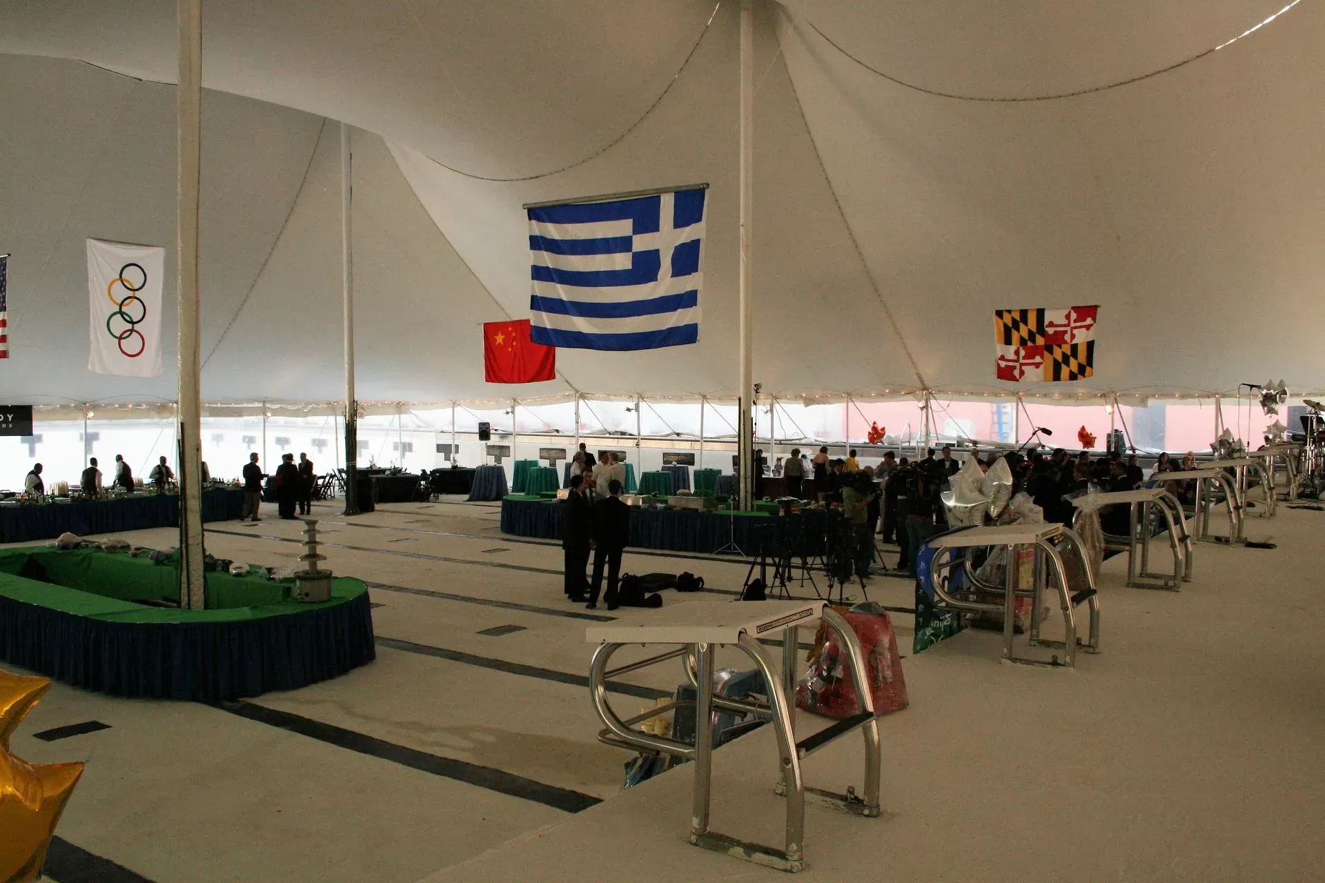 Large white tent interior with hanging flags from various nations and scattered tables, set up for an event.