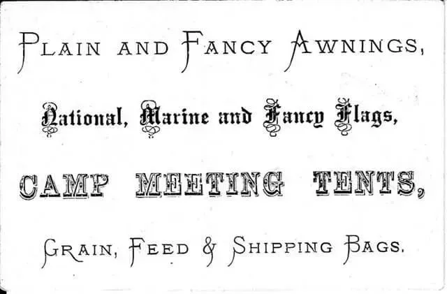 A black-and-white sign listing business offerings: Plain and Fancy Awnings, flags, camp meeting tents, and storage bags.