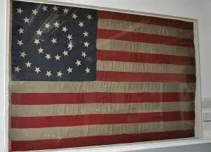 Historical U.S. flag in a display case featuring 38 stars arranged in a circular pattern on a blue canton.