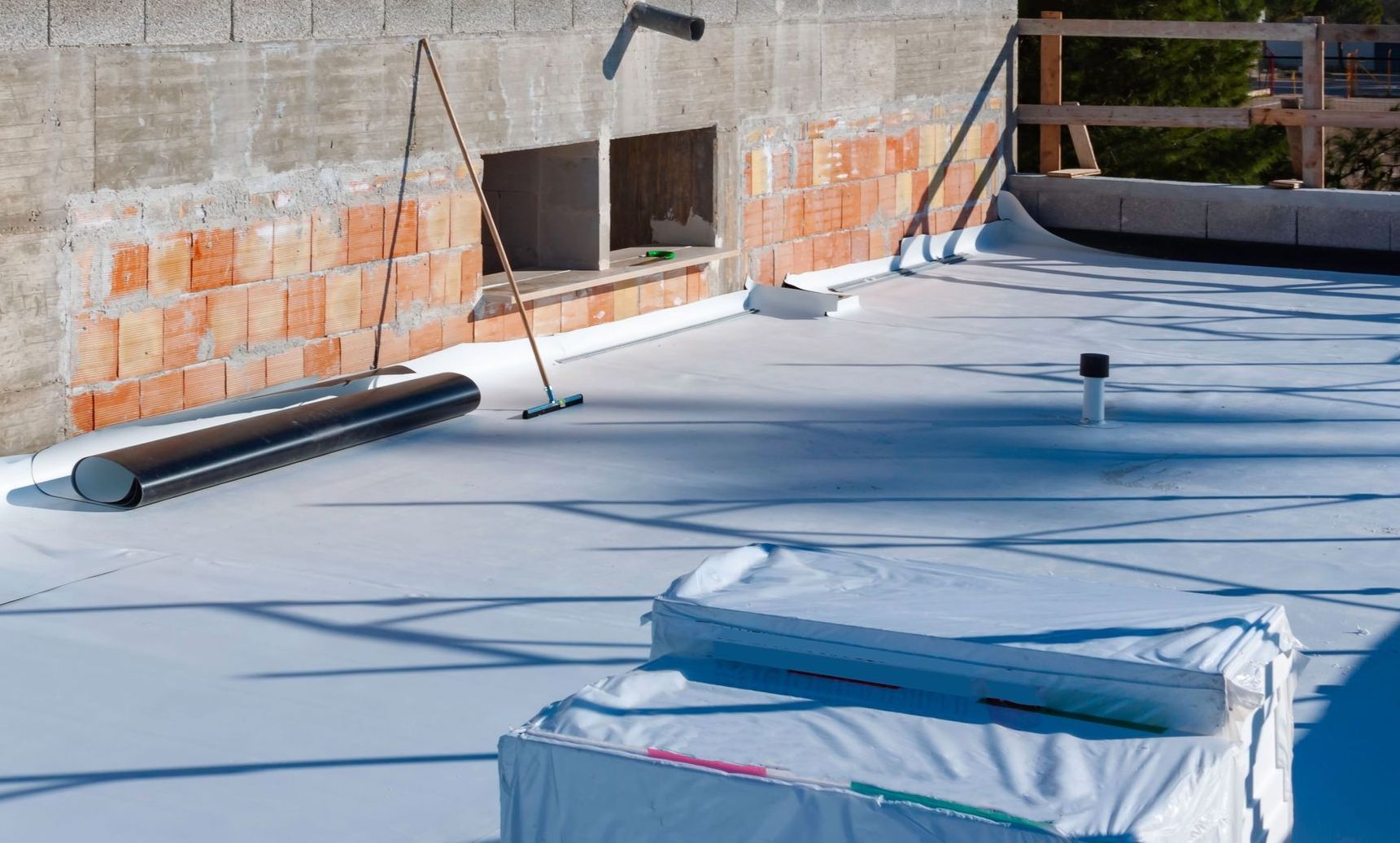A white roof is being installed on a building under construction.
