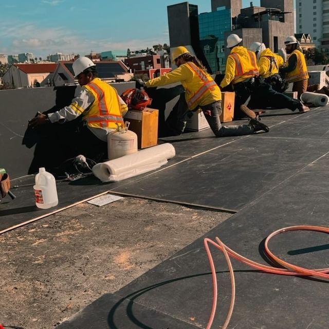A group of construction workers are working on a roof