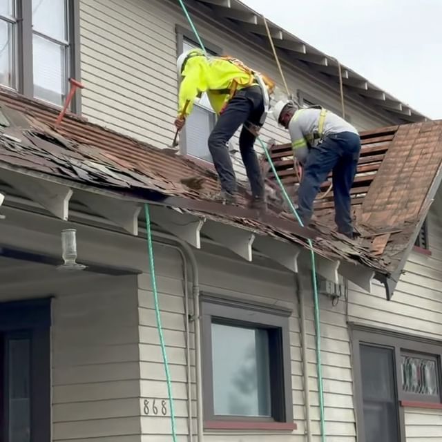 Two men are working on the roof of a house with the number 888 on the side