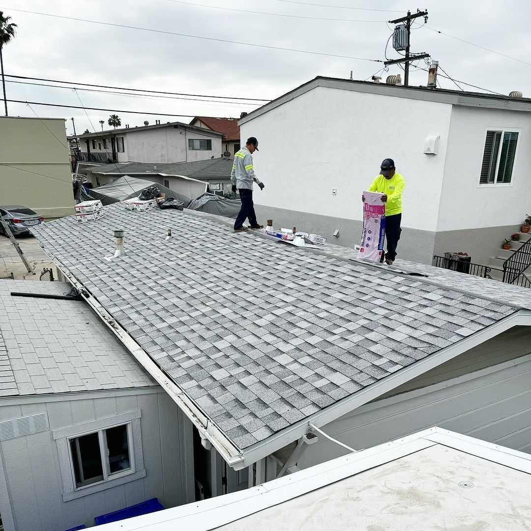 Two men are working on the roof of a house.