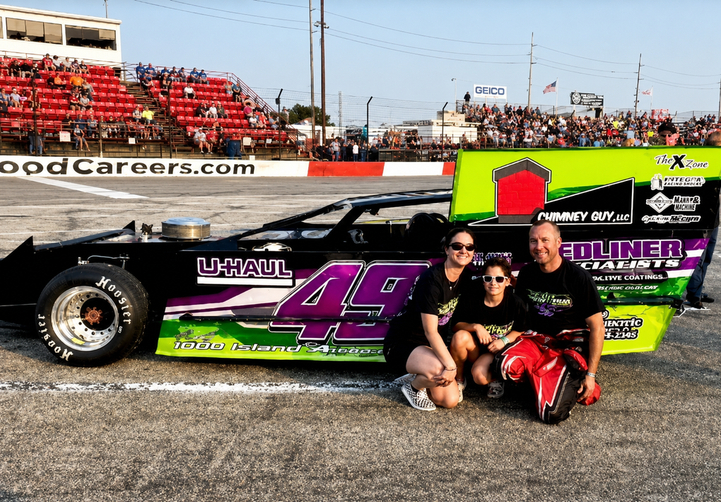 Race car in purple and green with a family posing beside it on a dirt track