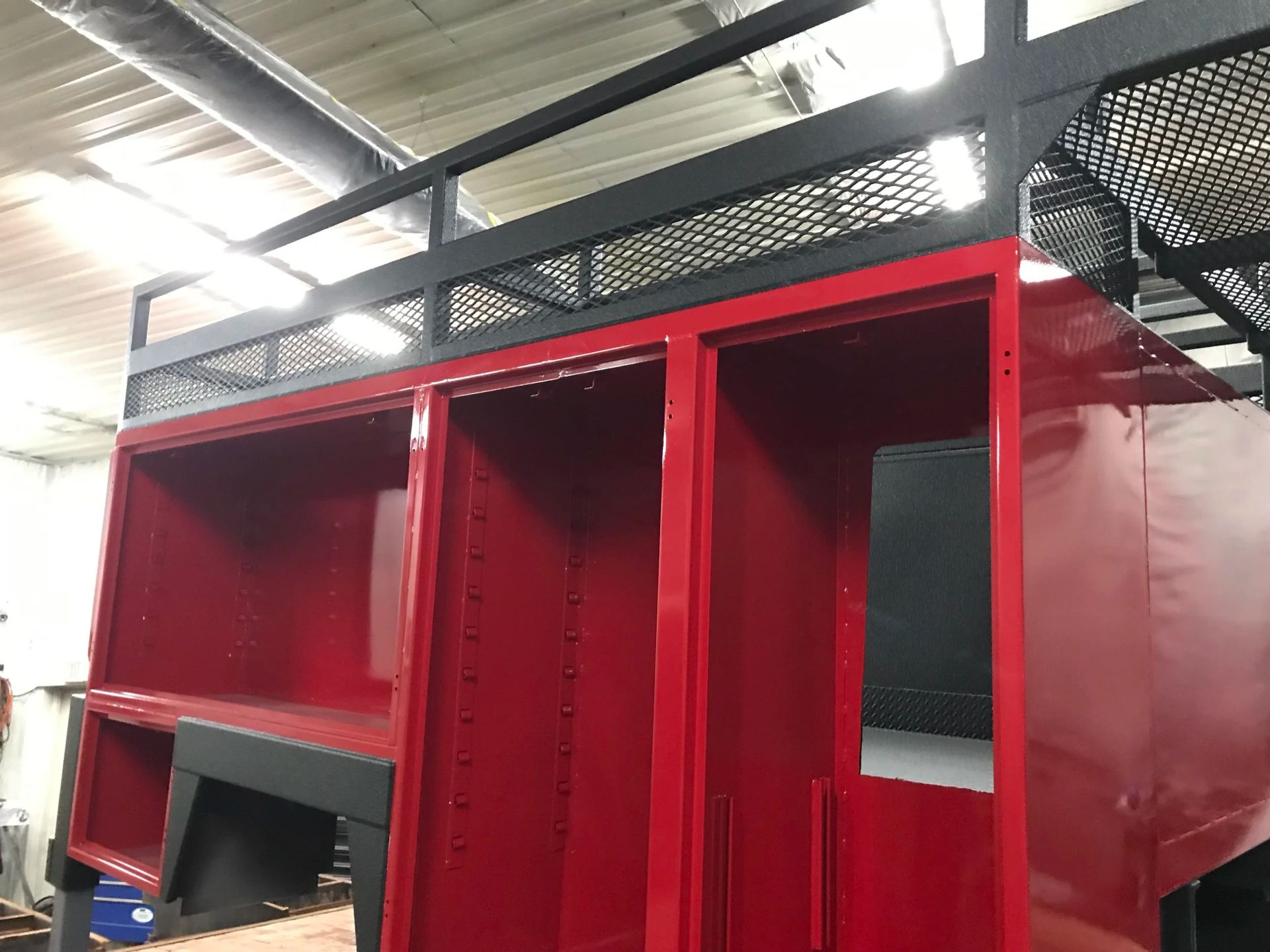 Red metal storage cabinet with open shelves in an industrial warehouse setting