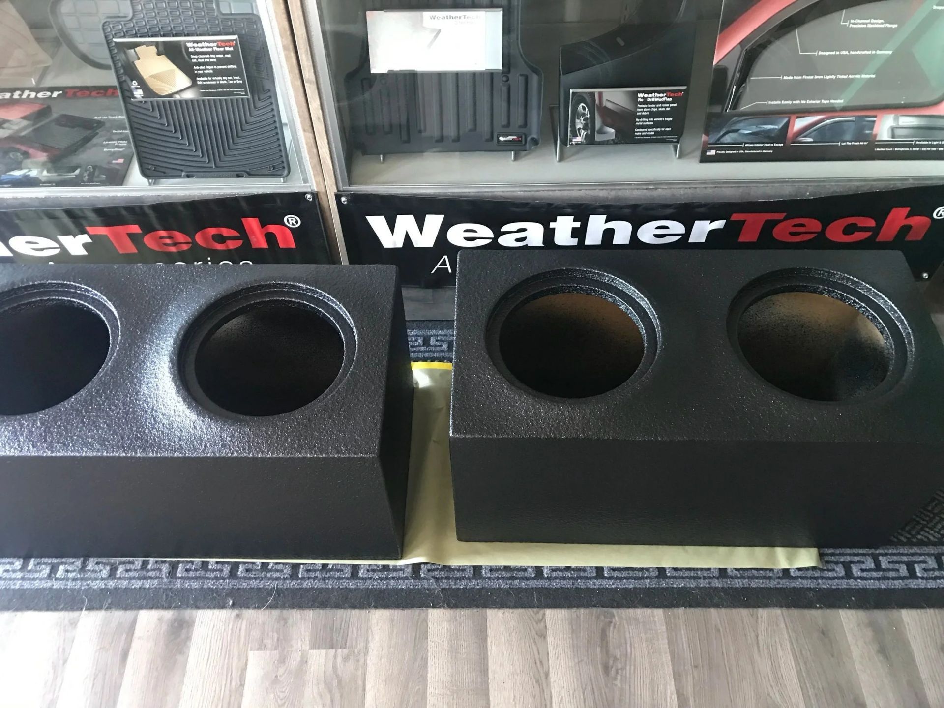 Two black WeatherTech dual cup holder inserts on a countertop display.
