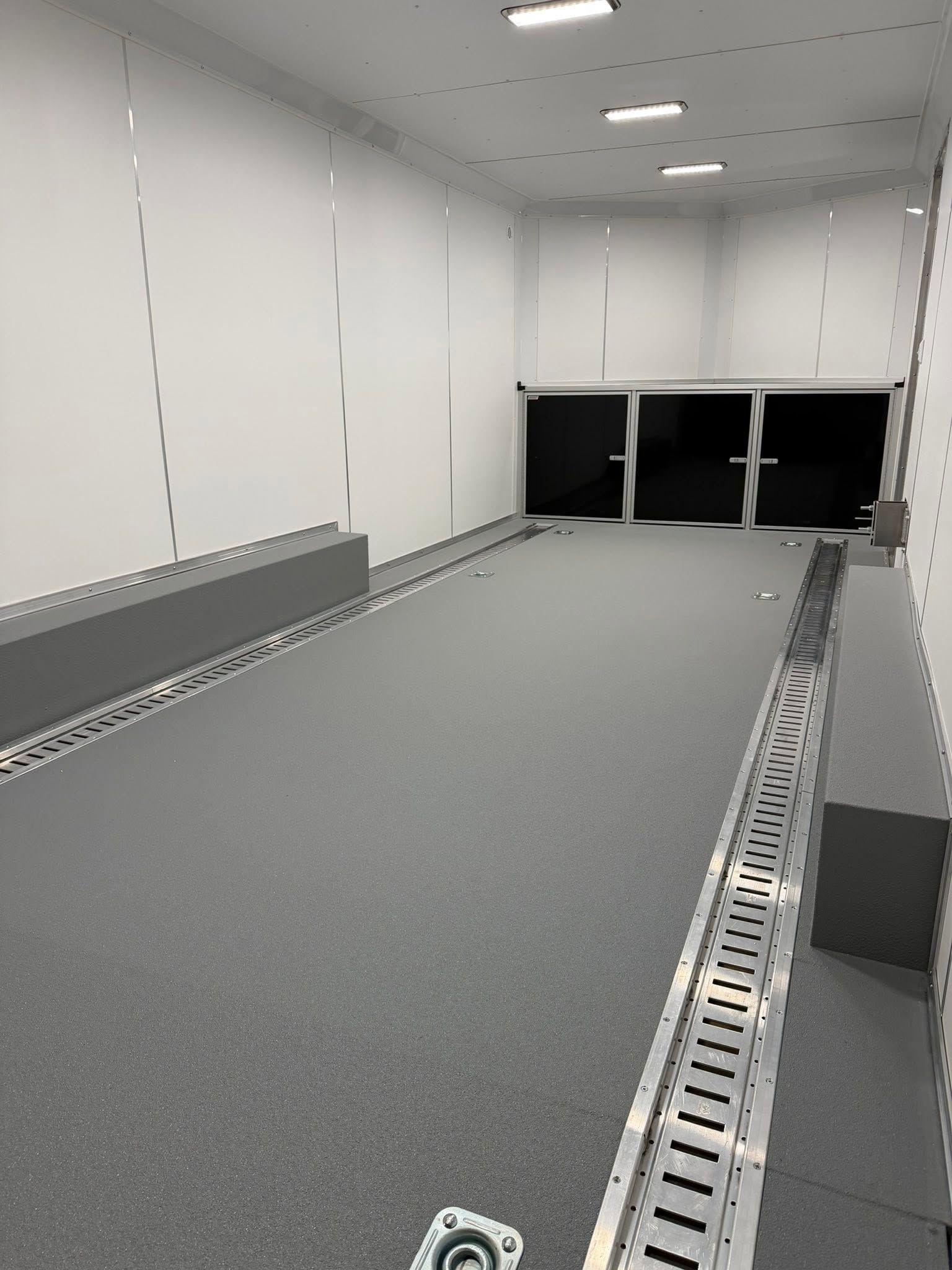 Empty white cargo trailer interior with gray floor and loading ramp area.