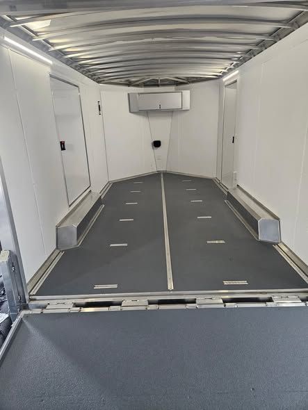 Empty white cargo trailer interior with gray floor and ramp lowered at the entrance