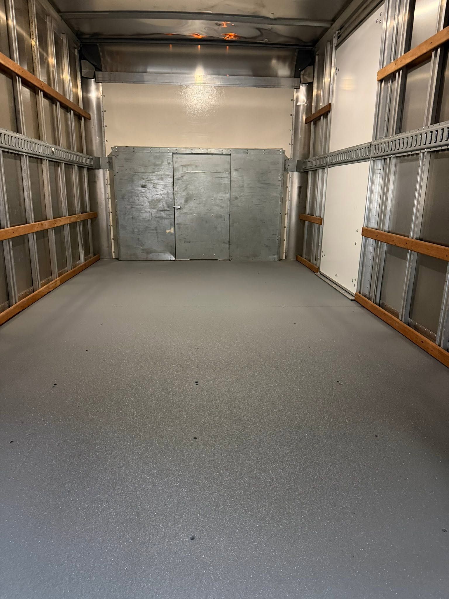 Empty cargo truck interior with gray metal walls and closed rear door