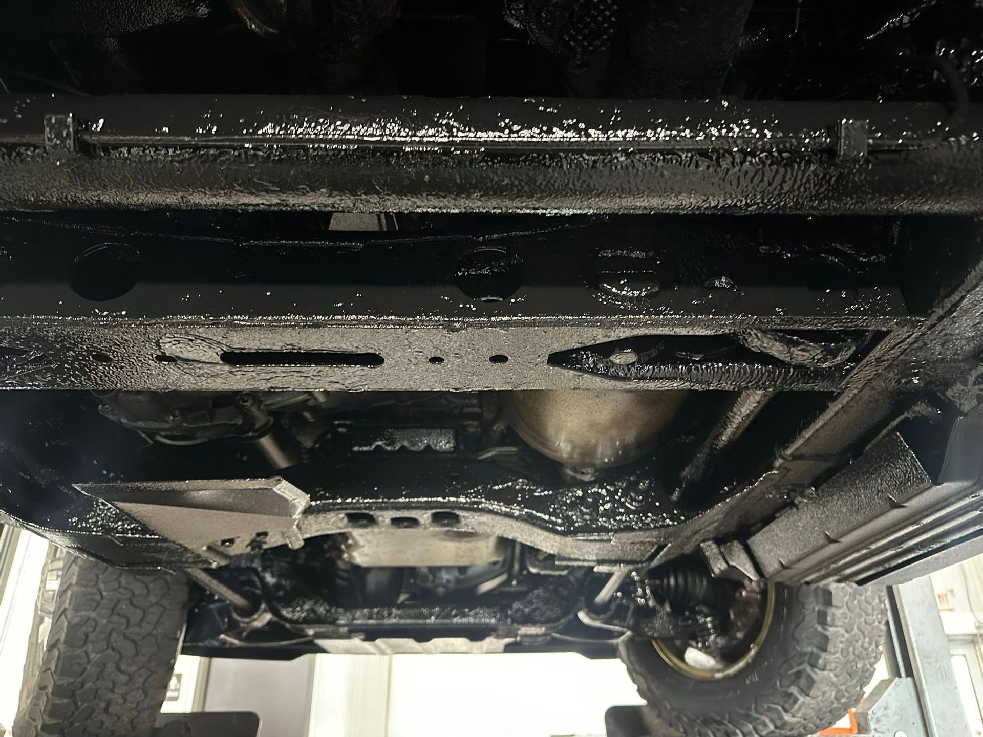 Undercarriage of a vehicle, showing the chassis, suspension, and a rear tire.