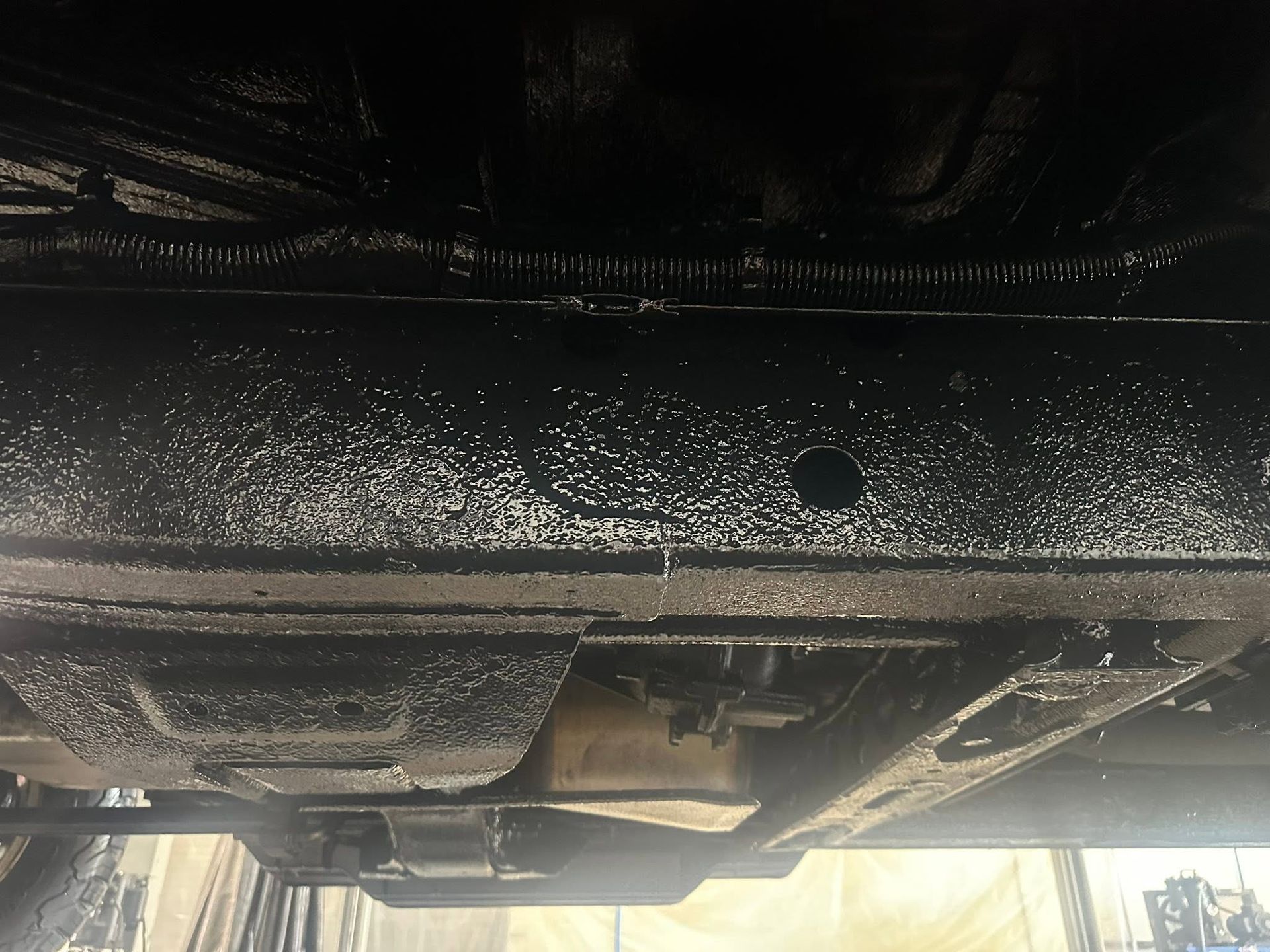 Underside of a vehicle showing the exhaust, suspension, and road grime under the chassis