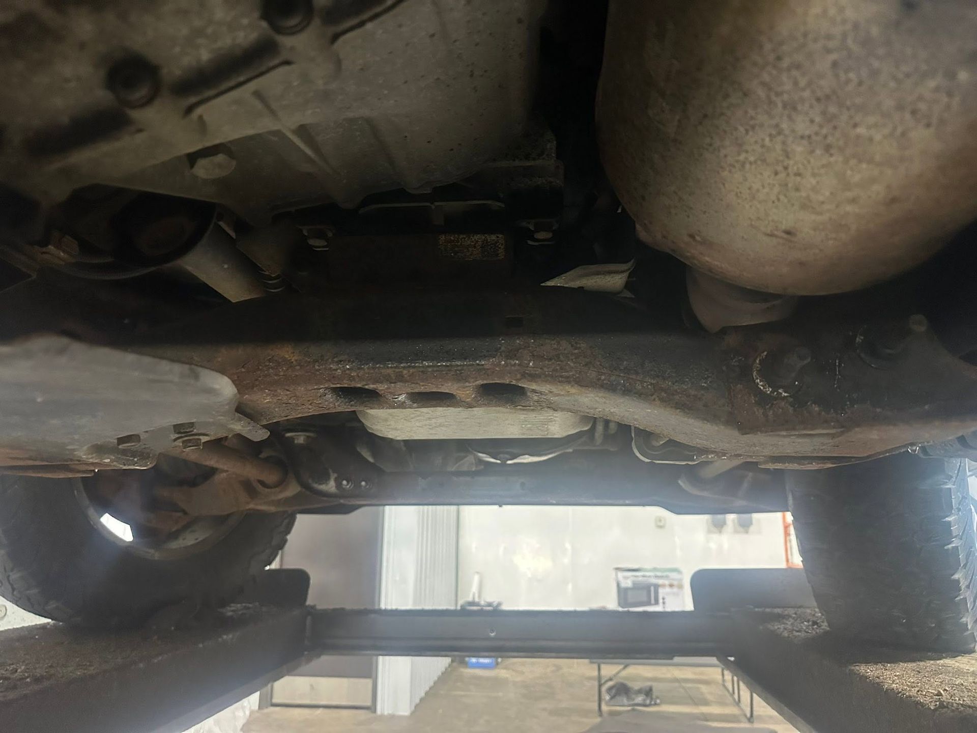 Underbody view of a vehicle lifted on a rack, showing the exhaust and suspension.
