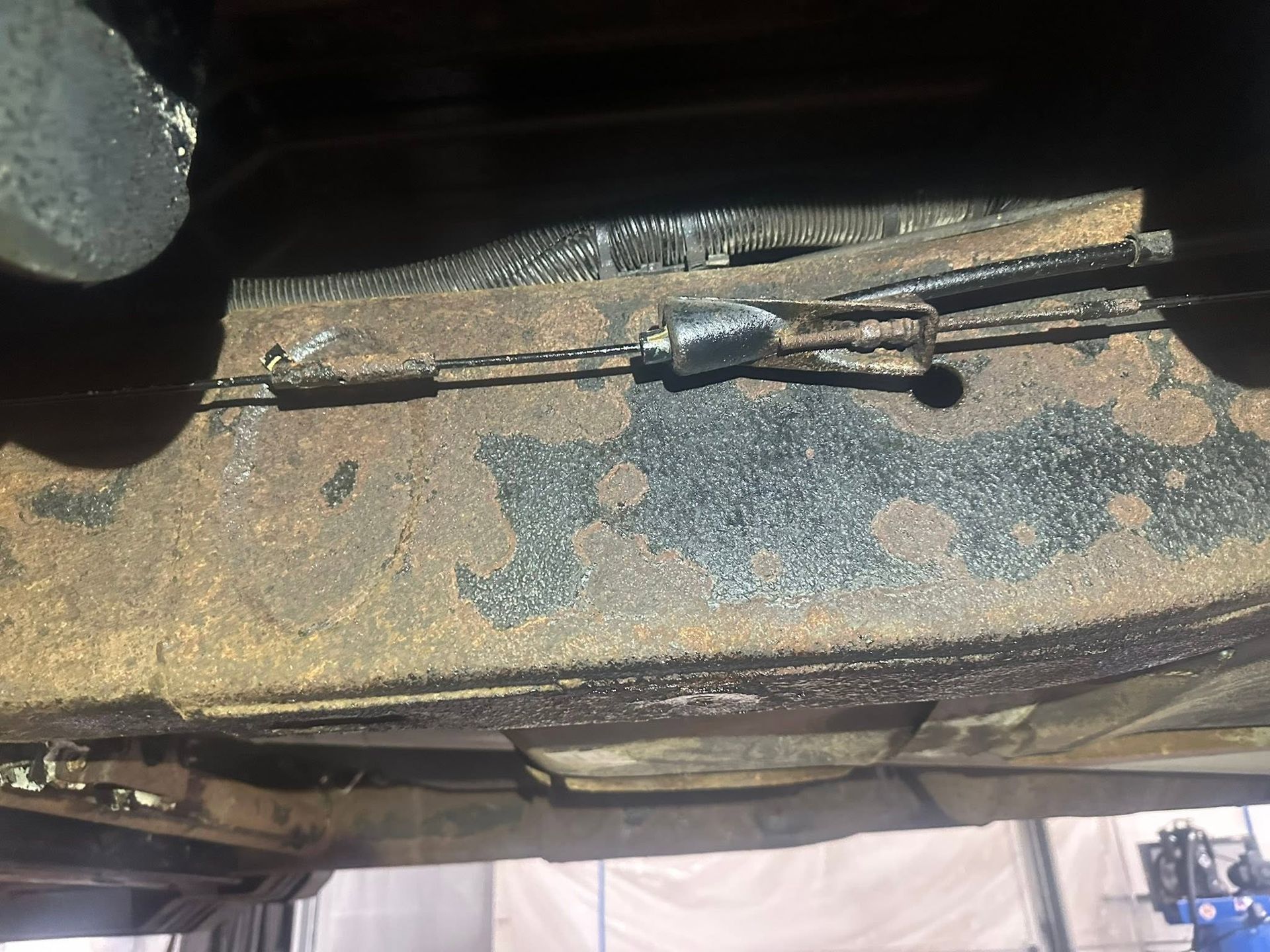 Close-up of a dusty, rusted metal windshield wiper assembly on a vehicle.