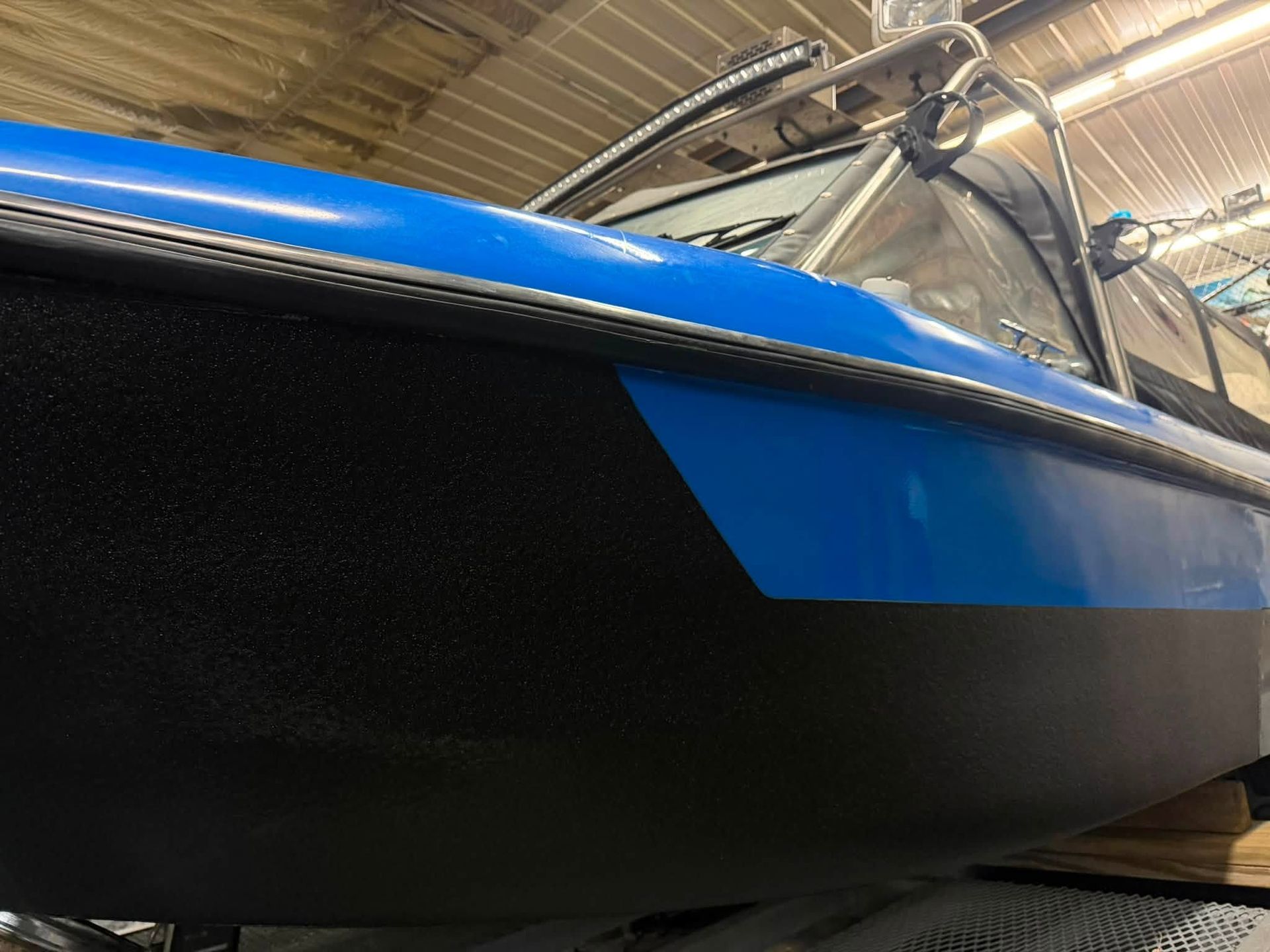 Blue and black boat hull in a dry dock, seen from a low angle