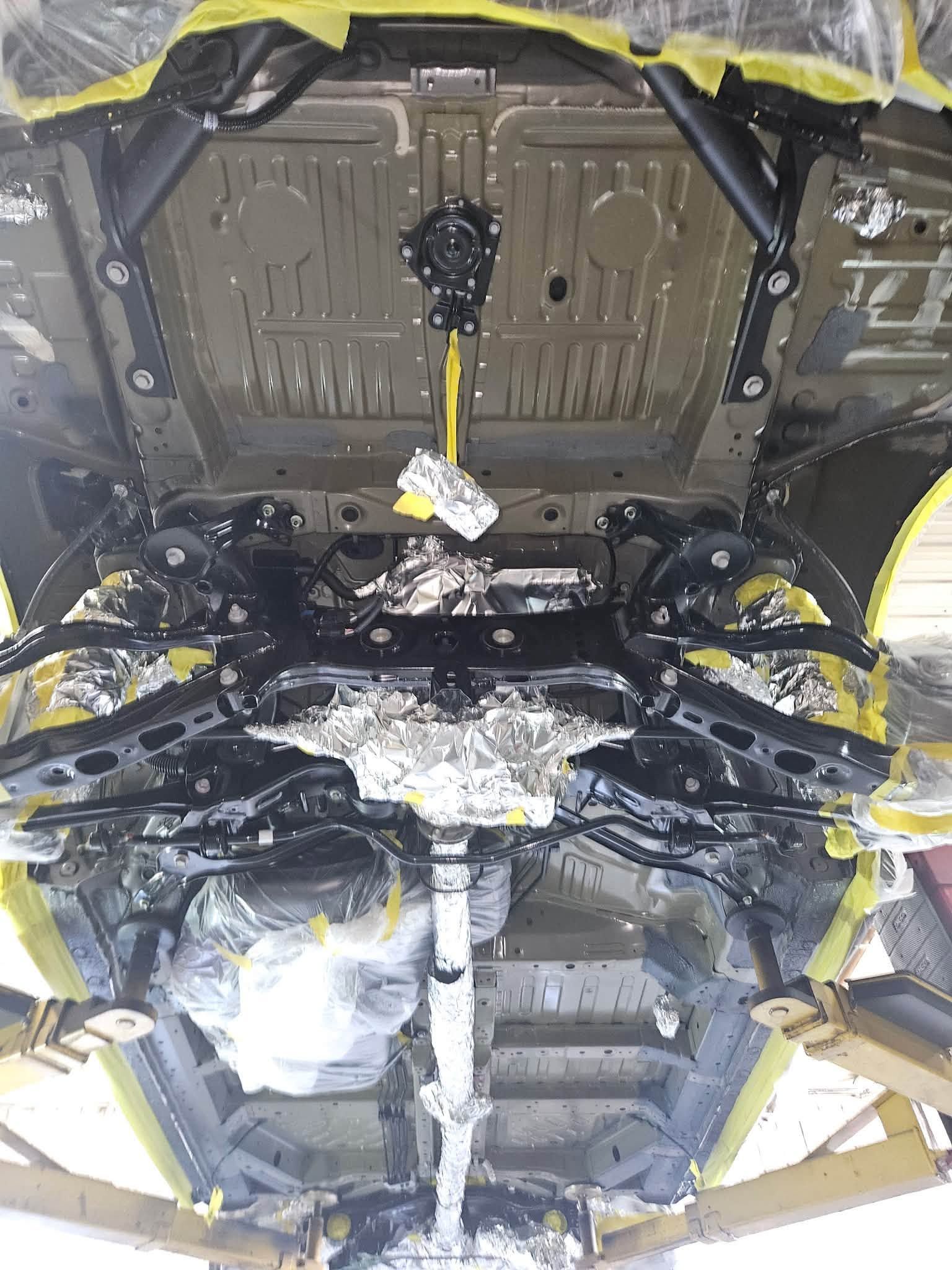 Damaged car interior with exposed metal, torn insulation, and hanging wires under the dashboard