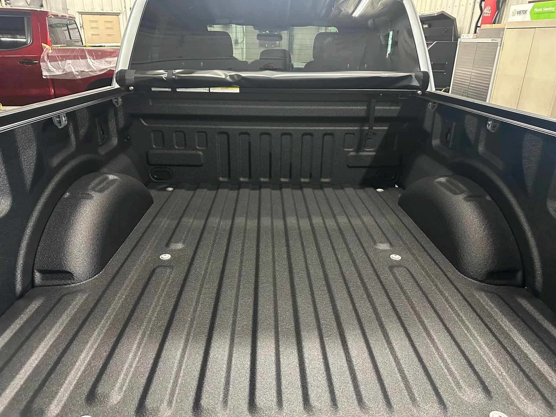 Empty pickup truck bed with black bed liner and wheel well covers