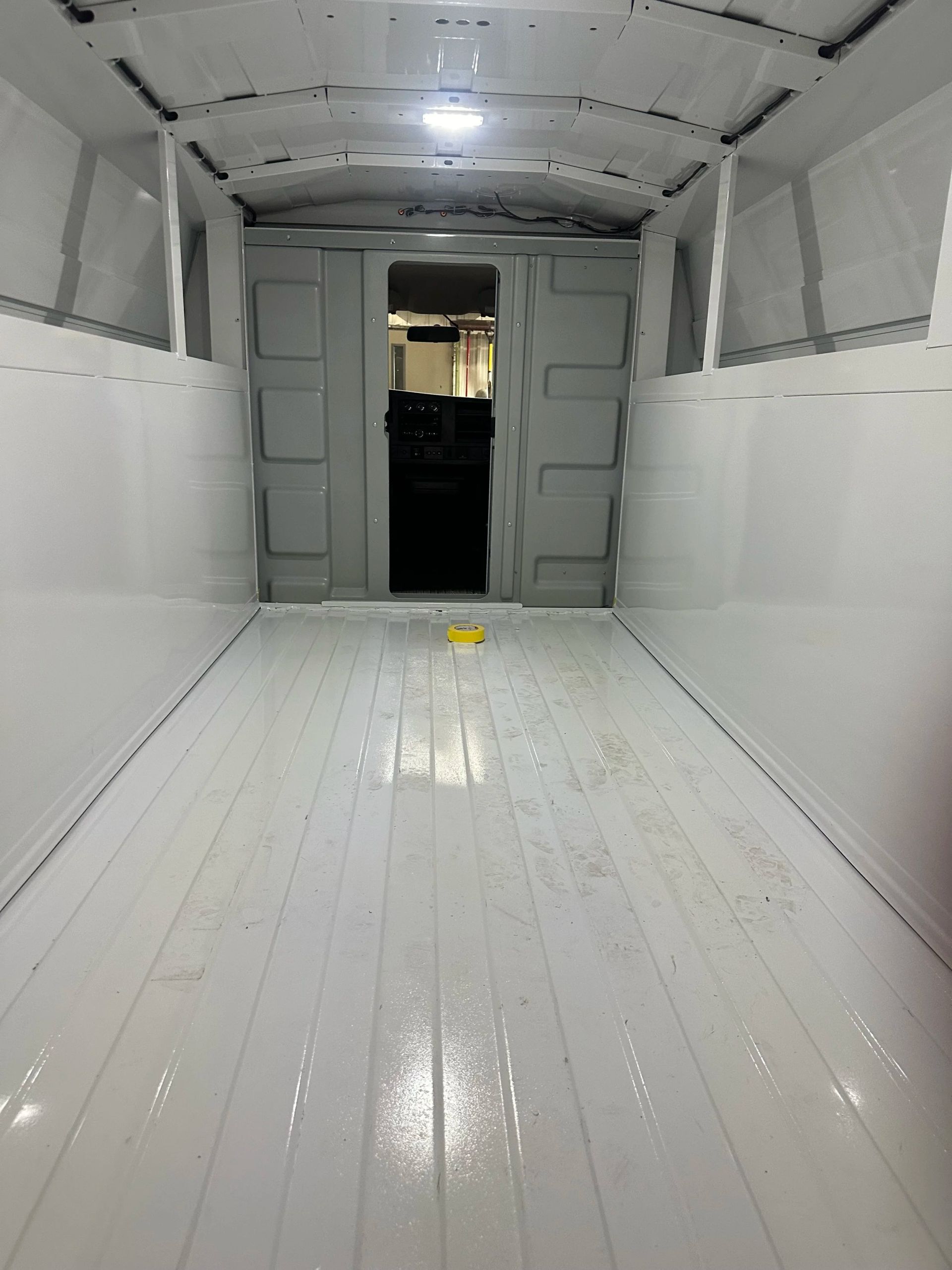 Empty white van cargo interior with open rear doors and glossy floor
