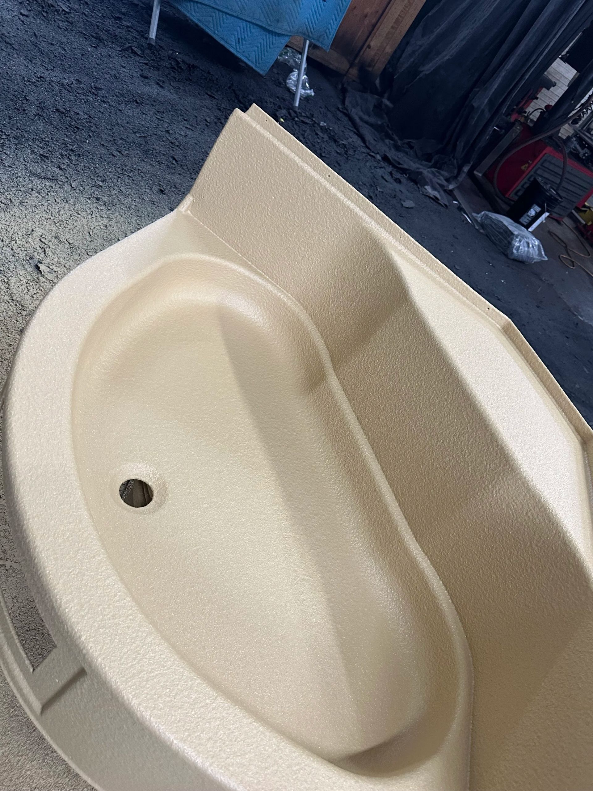 Beige bathroom sink with an oval basin and dark drain hole.