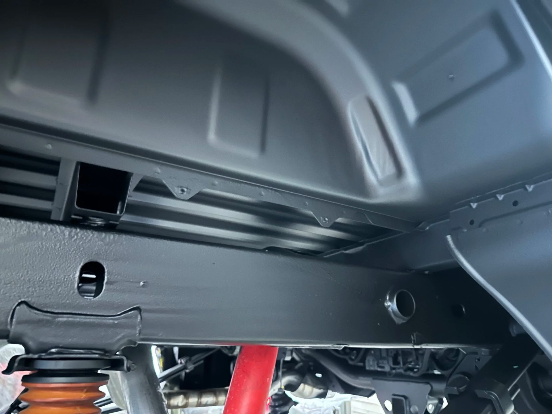 Car undercarriage with red suspension strut and black wheel well panels