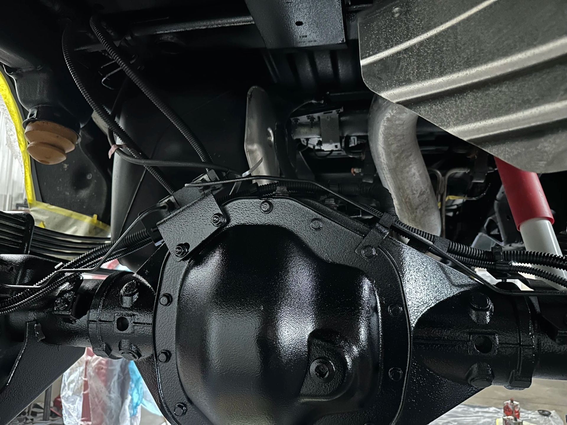 Rear view of a black car’s differential and suspension undercarriage, with tires visible on both sides
