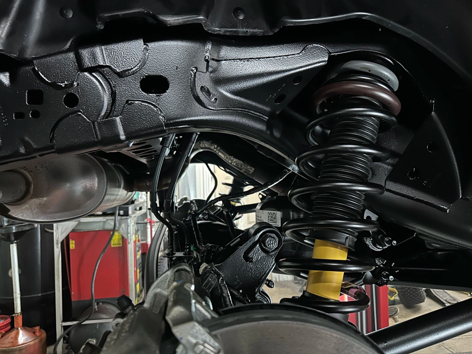 Car suspension and wheel well with exposed springs and control arms in a garage lift