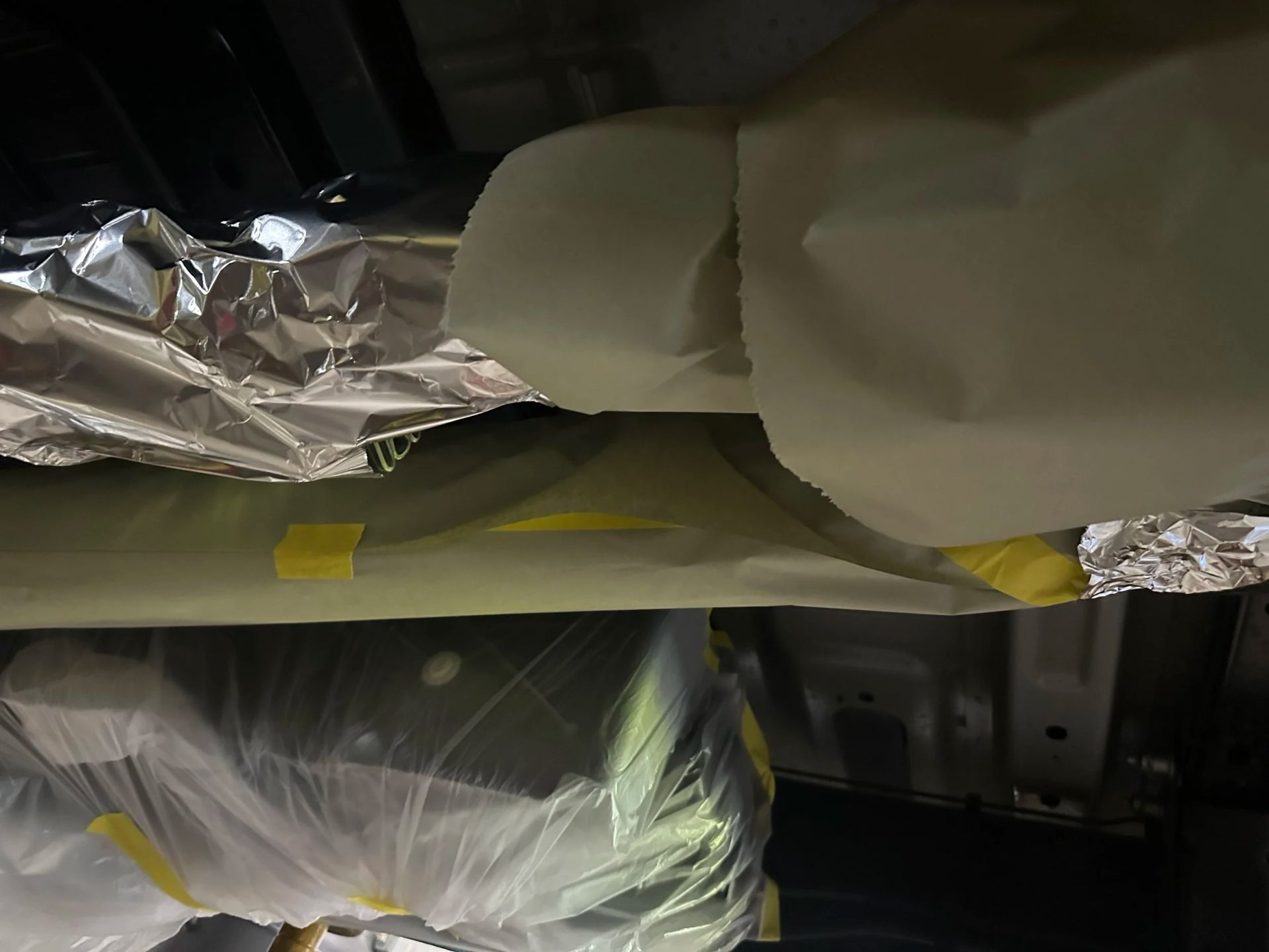 Foil-covered and plastic-wrapped items stored on a shelf in a dark compartment