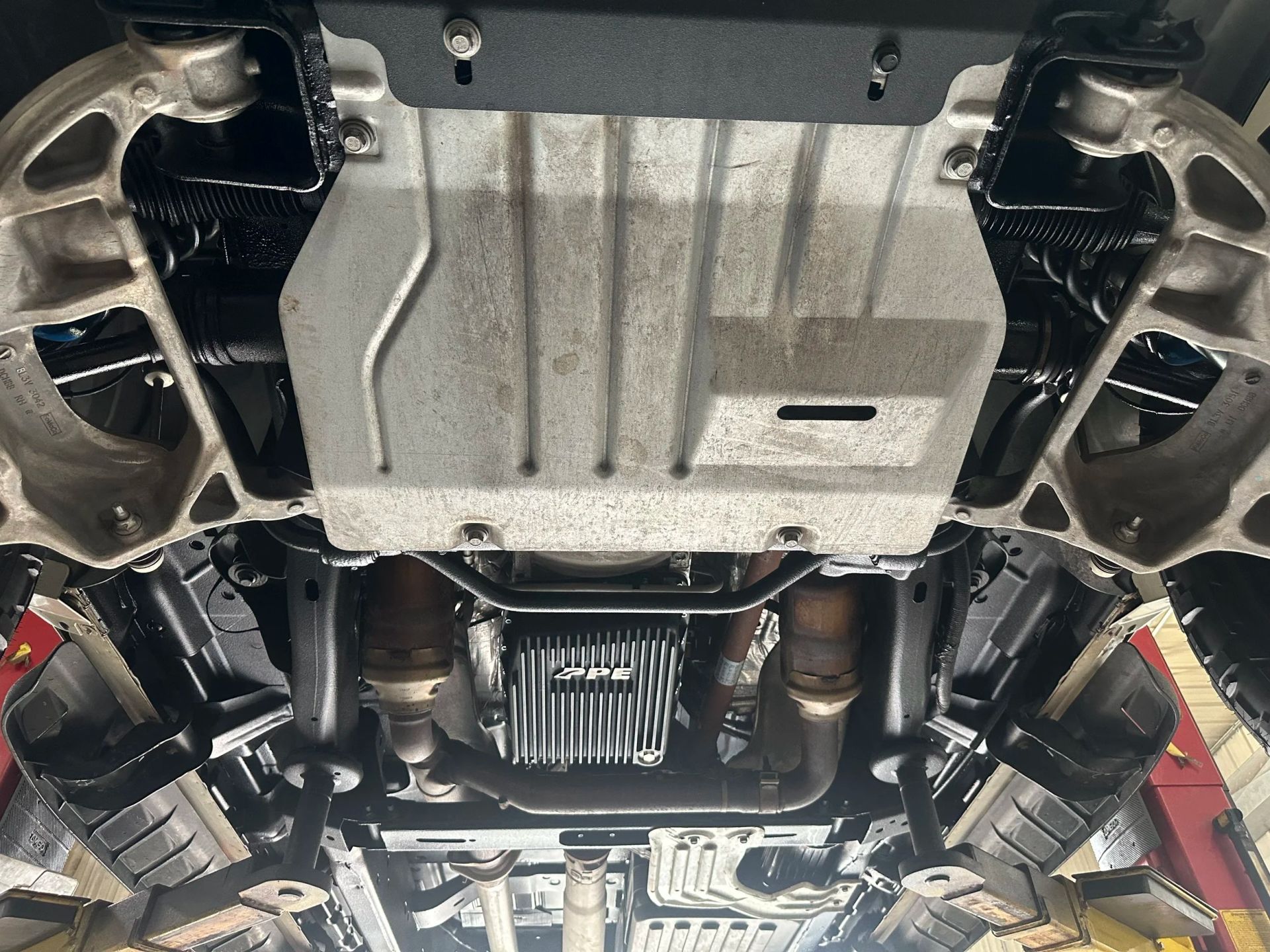 Underside of a car on a lift, showing the exhaust, drivetrain, and underbody panels.