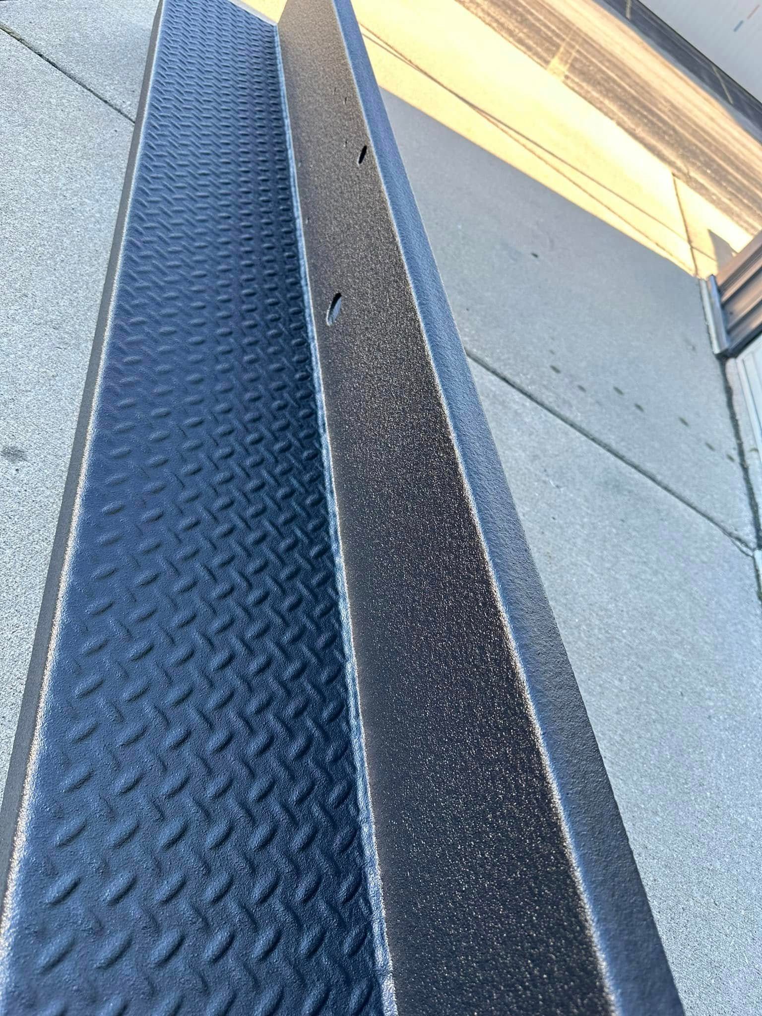 Close-up of a blue metal stair tread beside a gray wall and yellow railing.