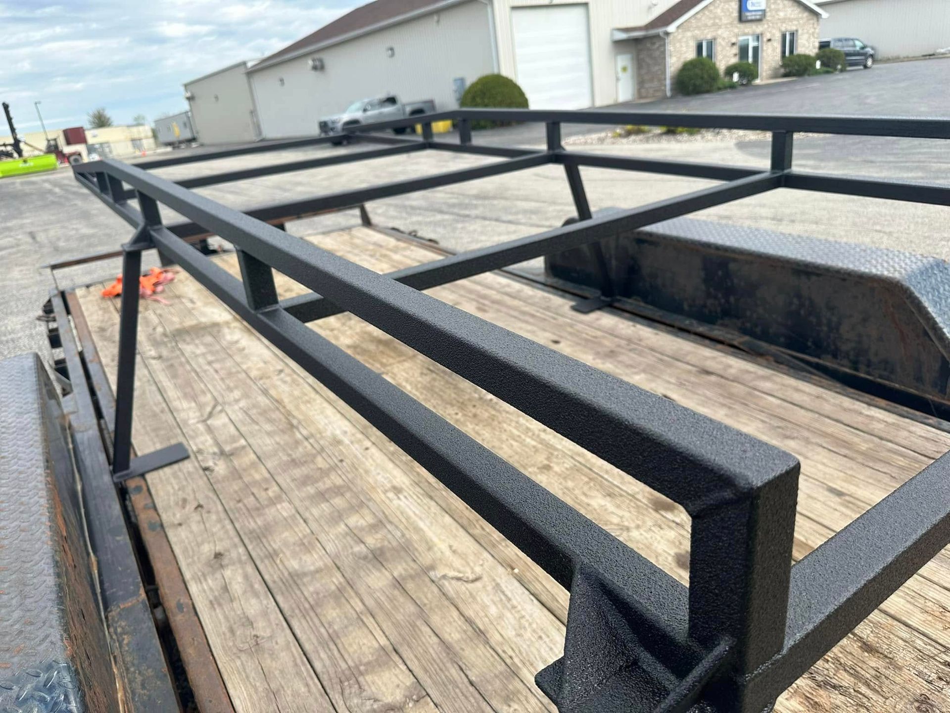 Black metal trailer ramp with wooden deck in a residential driveway.