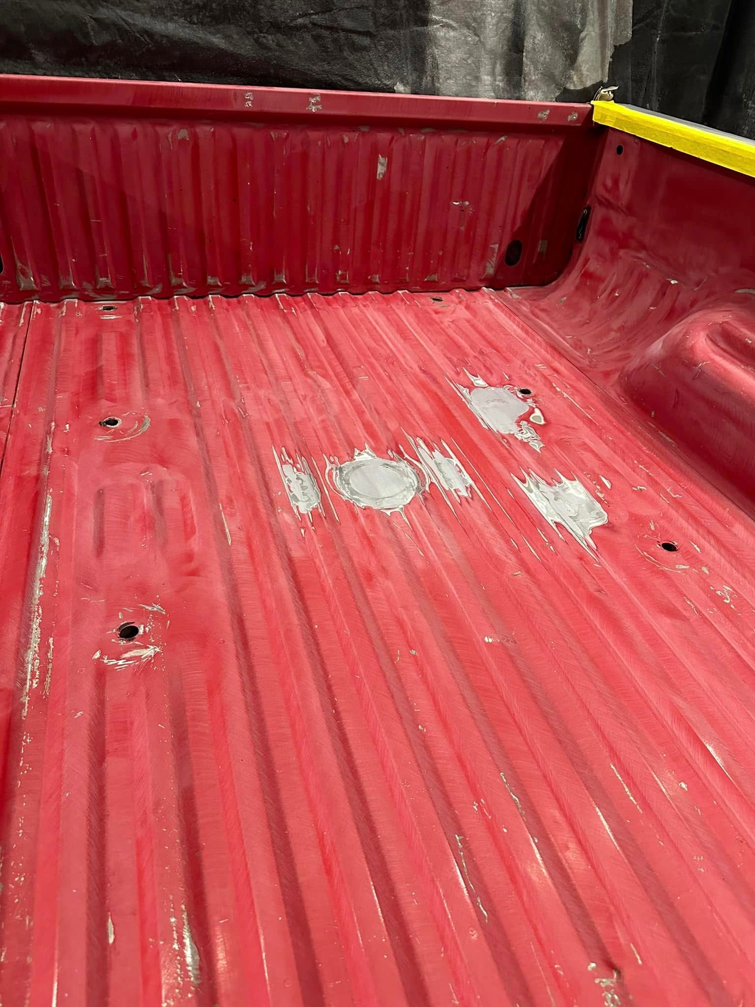 Red truck bed interior with worn red floor and peeling paint patches