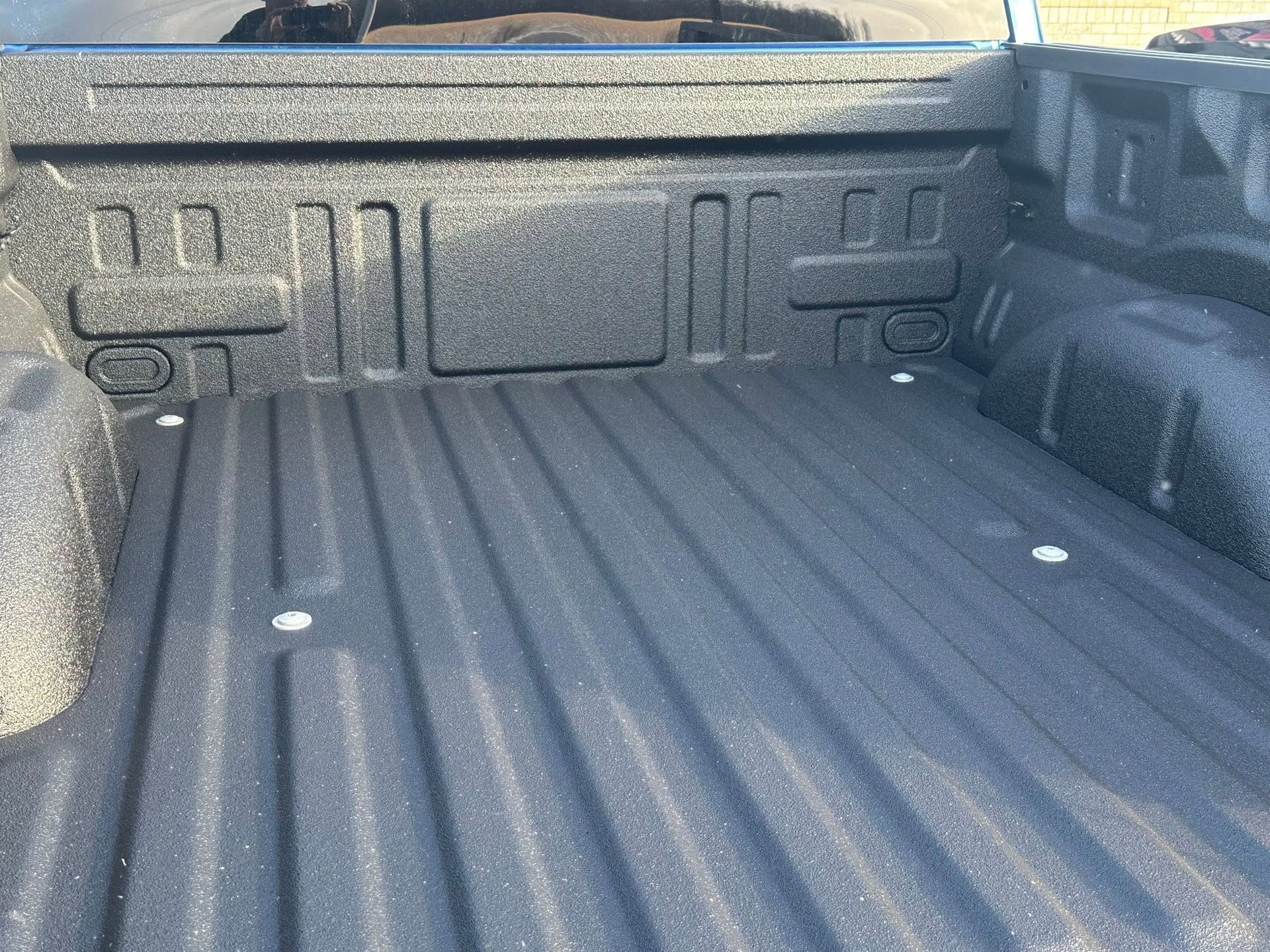 Empty gray pickup truck bed with textured liner and side rails