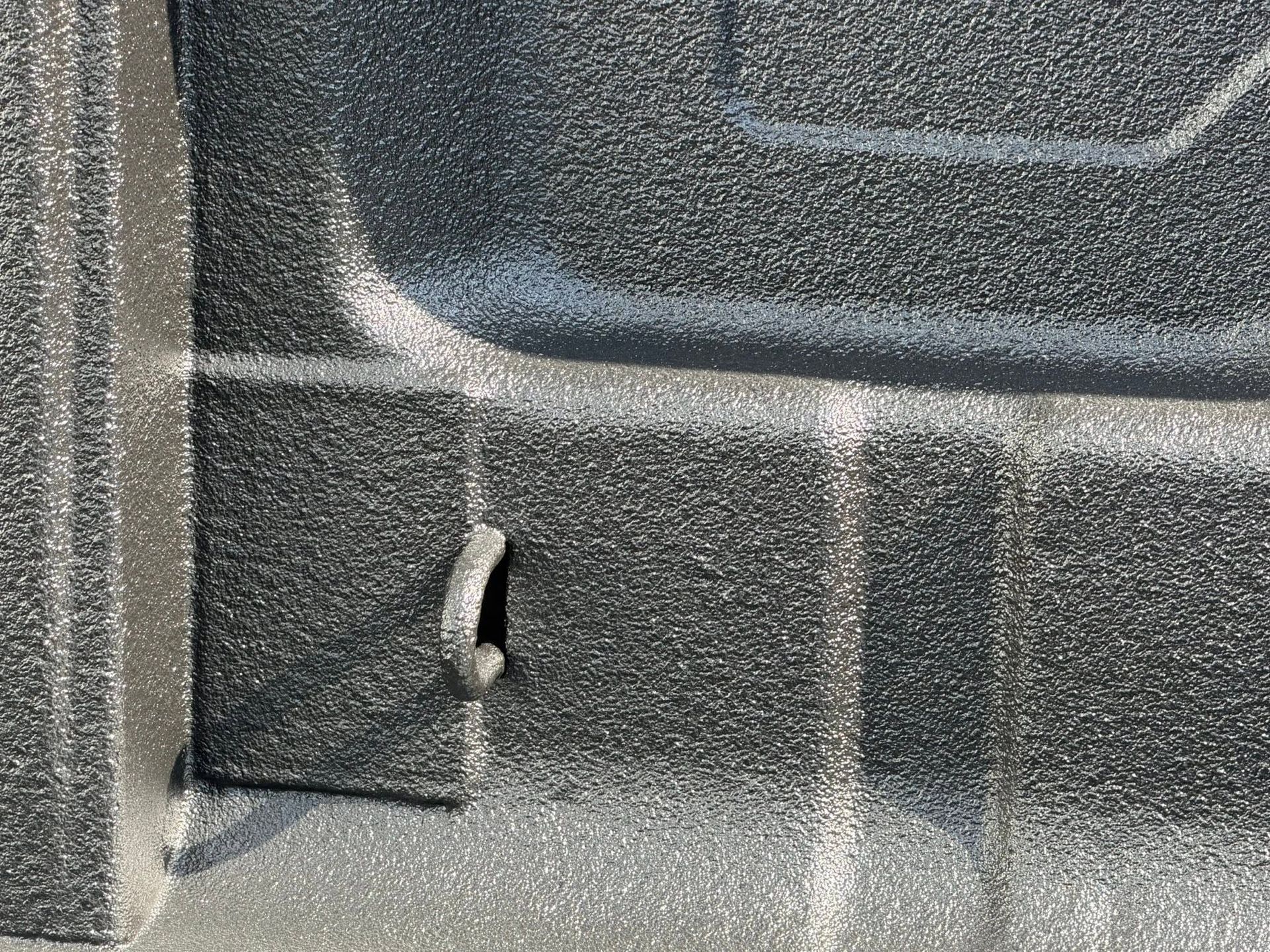Close-up of a gray textured surface with a small hole or tear near the lower left center.