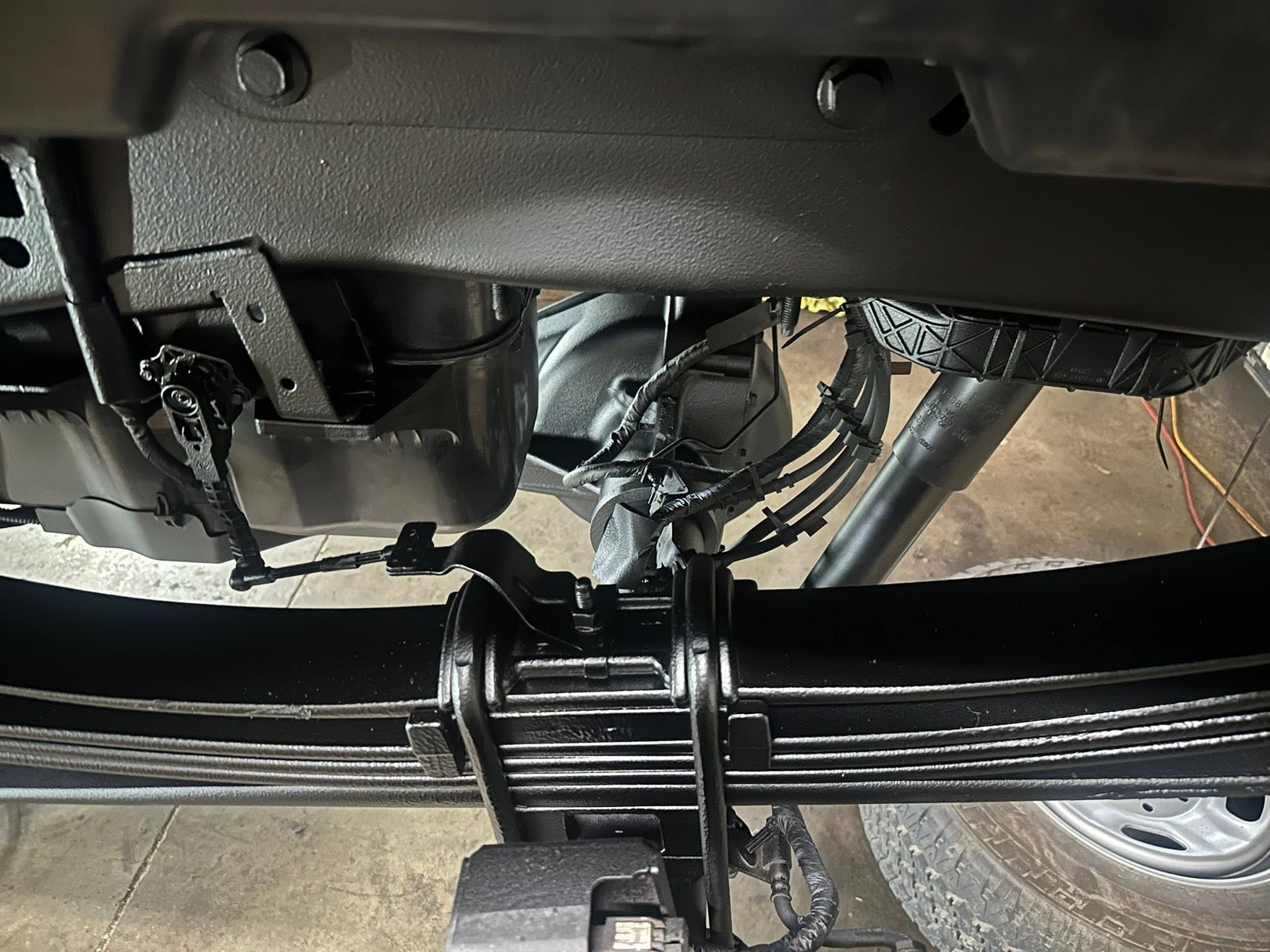 Undercarriage view of a vehicle’s rear axle, suspension, and exhaust system on a lift
