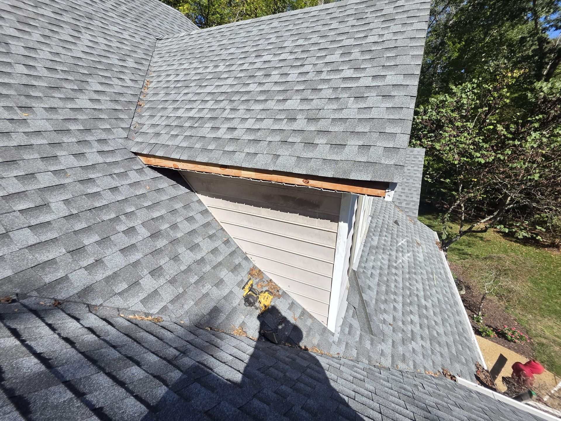 Damaged asphalt shingle roof, showing a section with missing shingles and exposed underlayment.