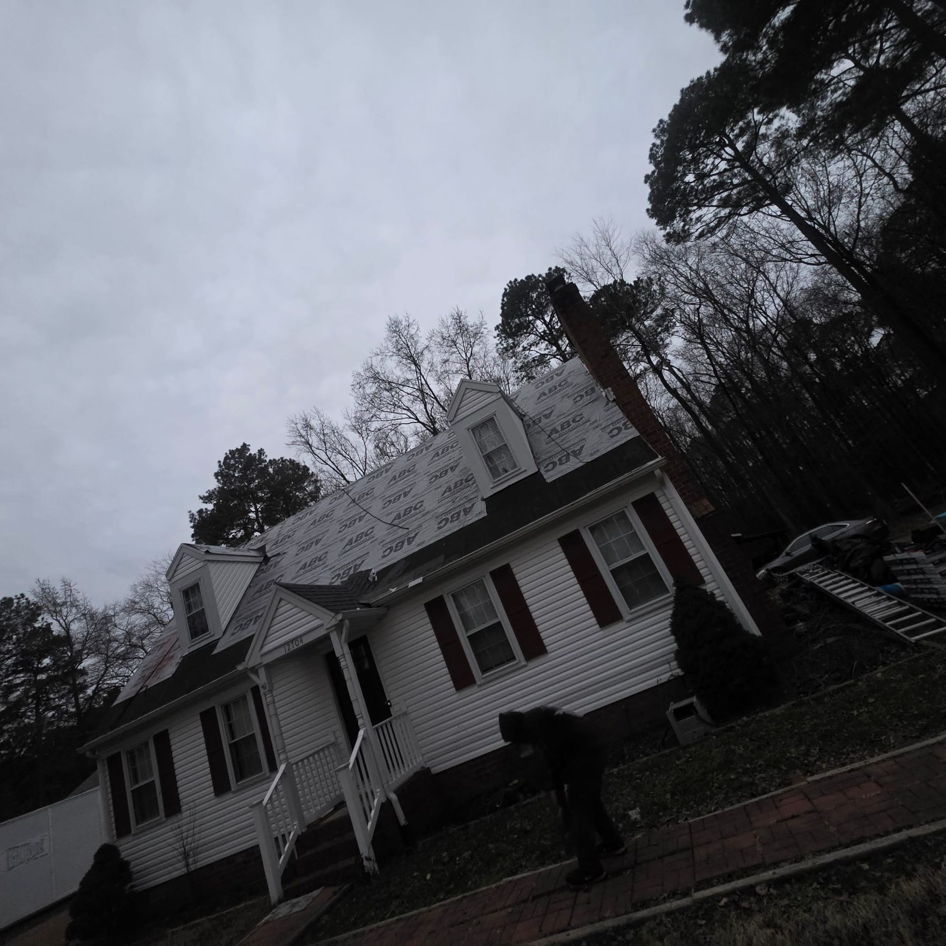 White house with red shutters under cloudy sky; person in dark clothing.