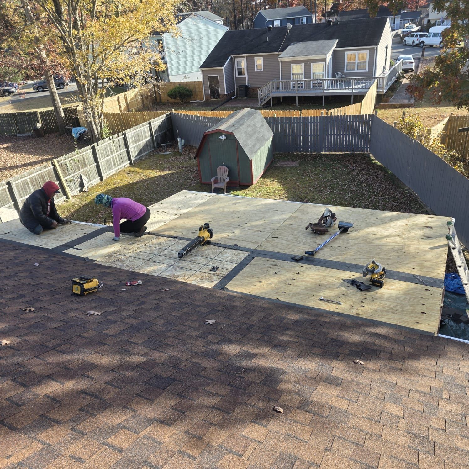 Roofers installing new roofing on a home, with tools and materials on the roof.