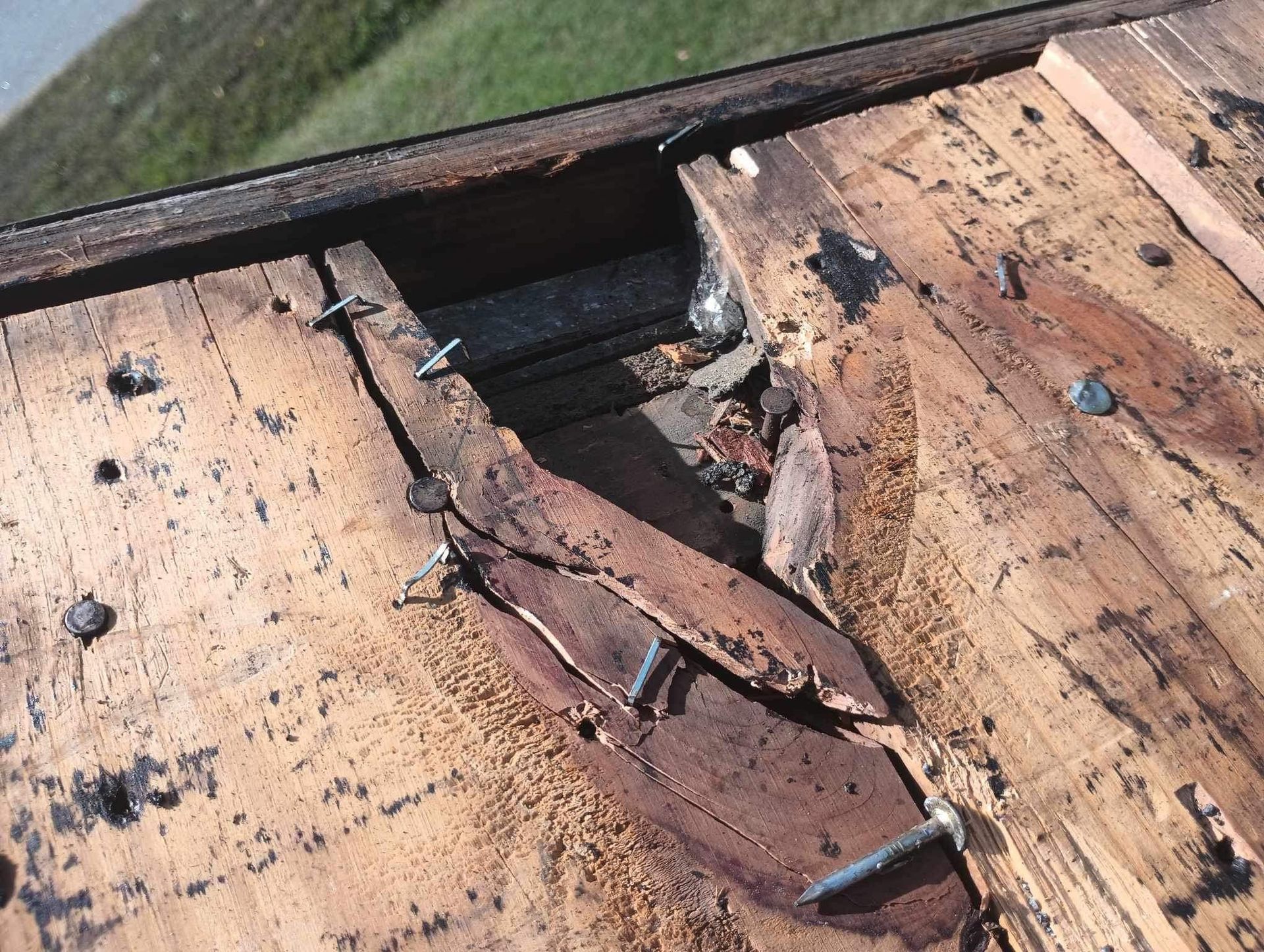 Damaged roof with broken wood and exposed interior.