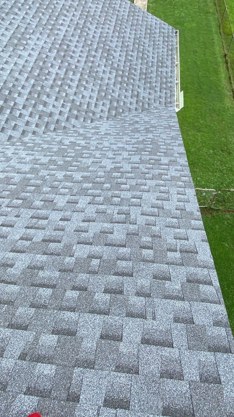 Gray shingled roof with a grass lawn in the background. The roof is angled.