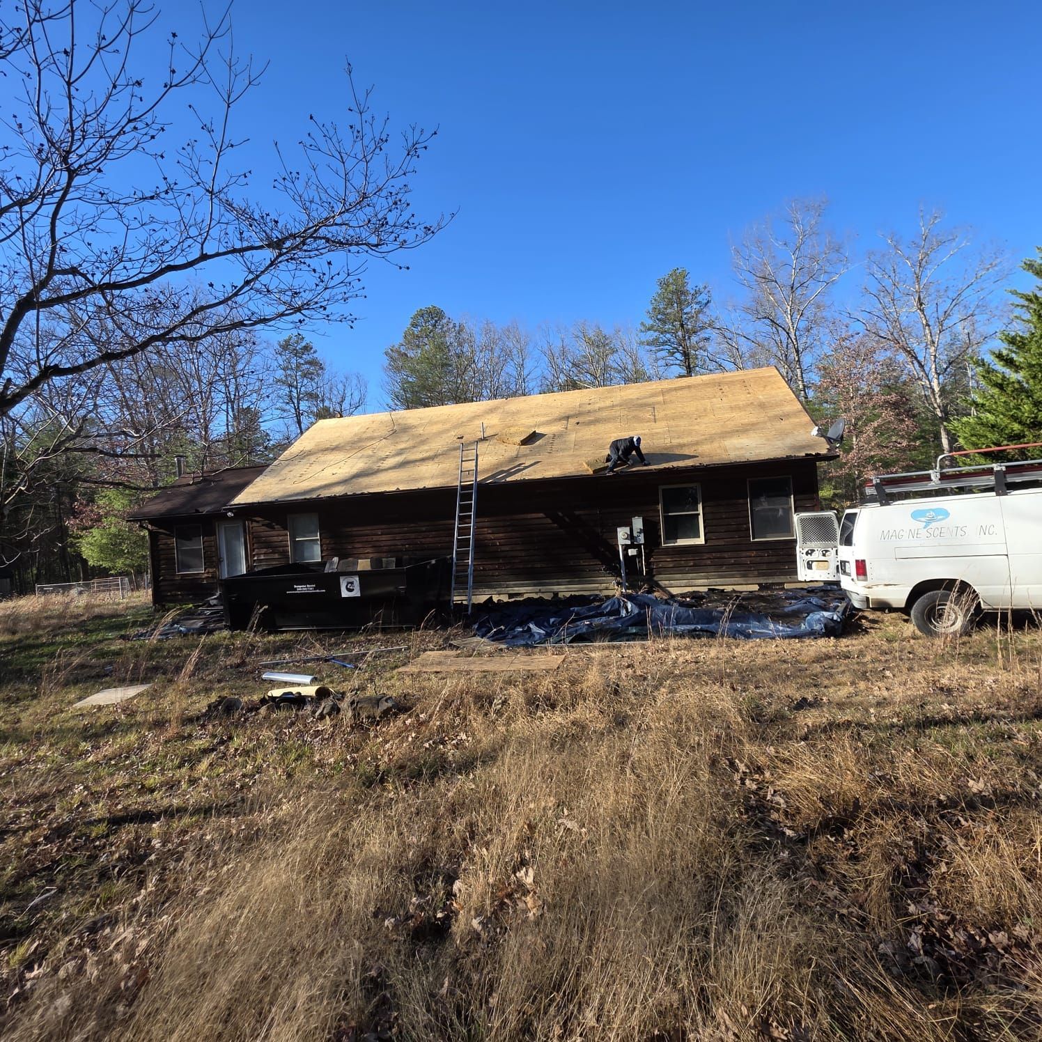 House with partially removed roof, construction site, sunny day. White van parked nearby.