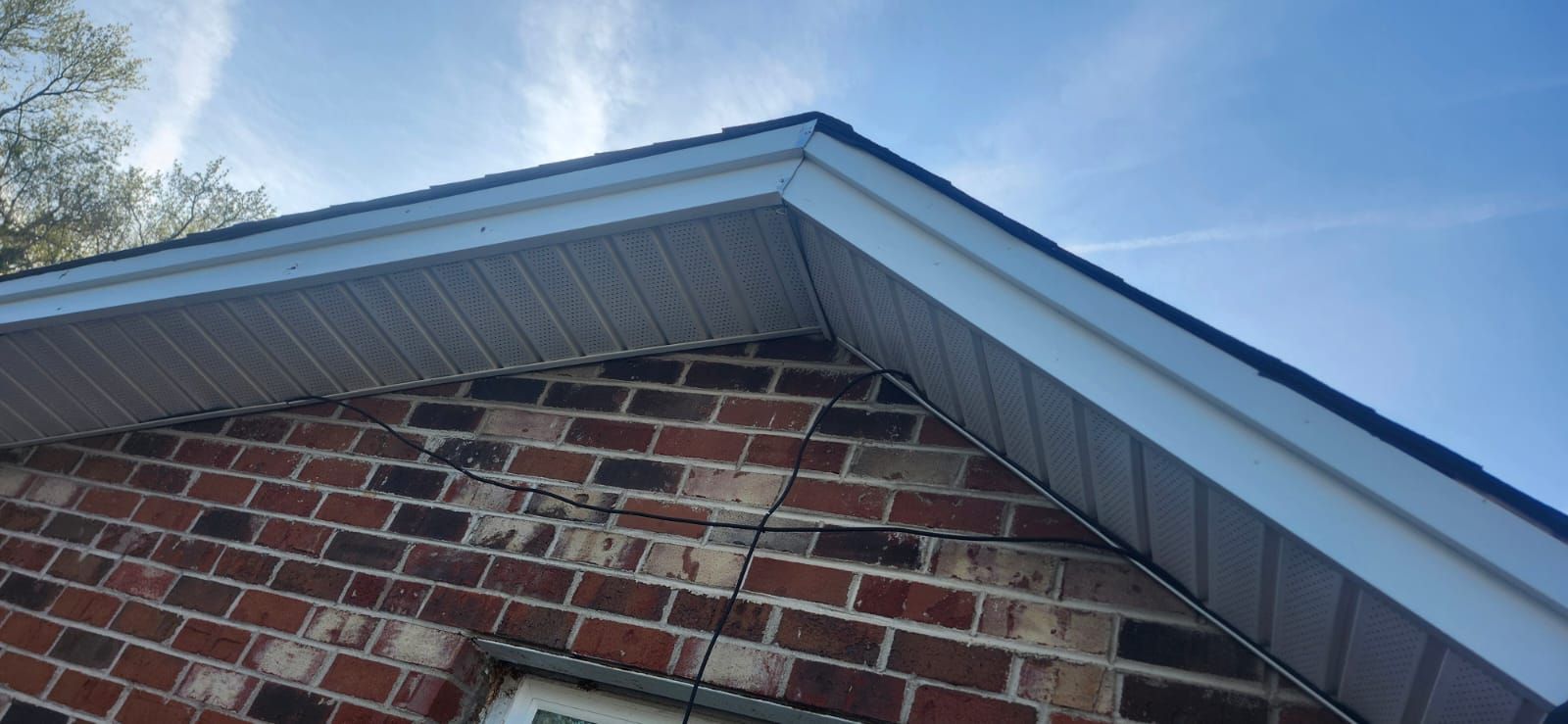 Brick building with white trim under a blue sky.
