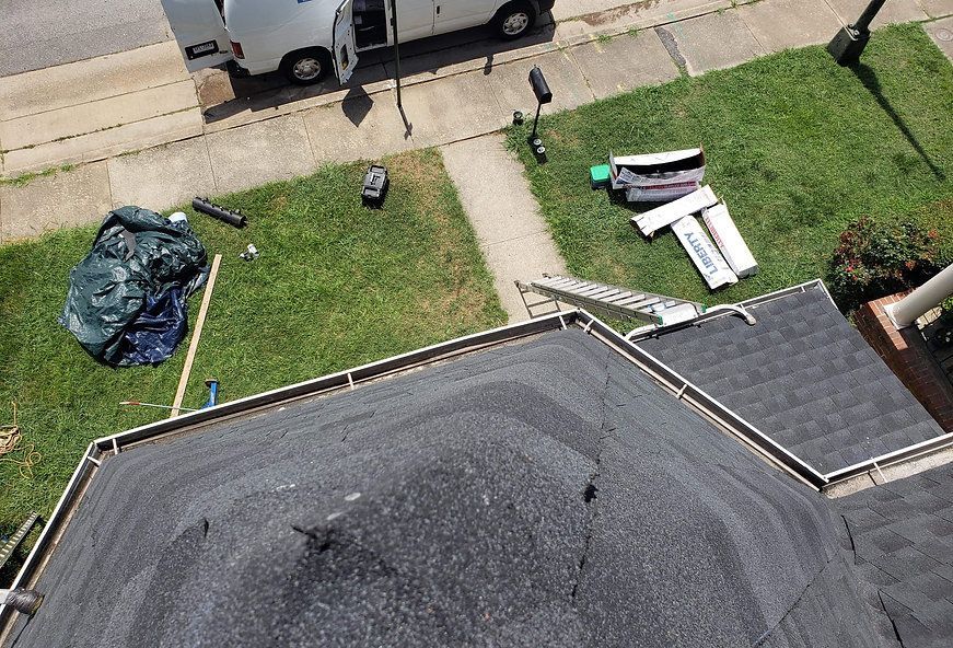 Rooftop with equipment and materials on the grass; a white van is parked nearby.