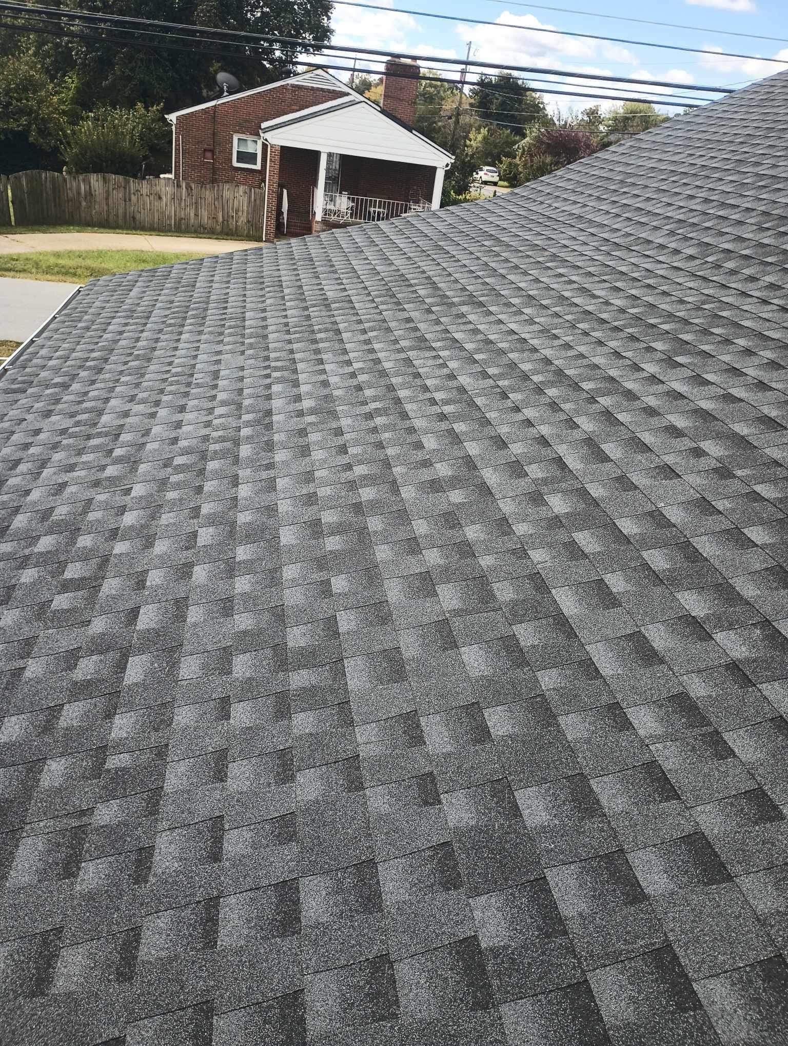 Gray asphalt shingle roof, angled view with other houses in the background.