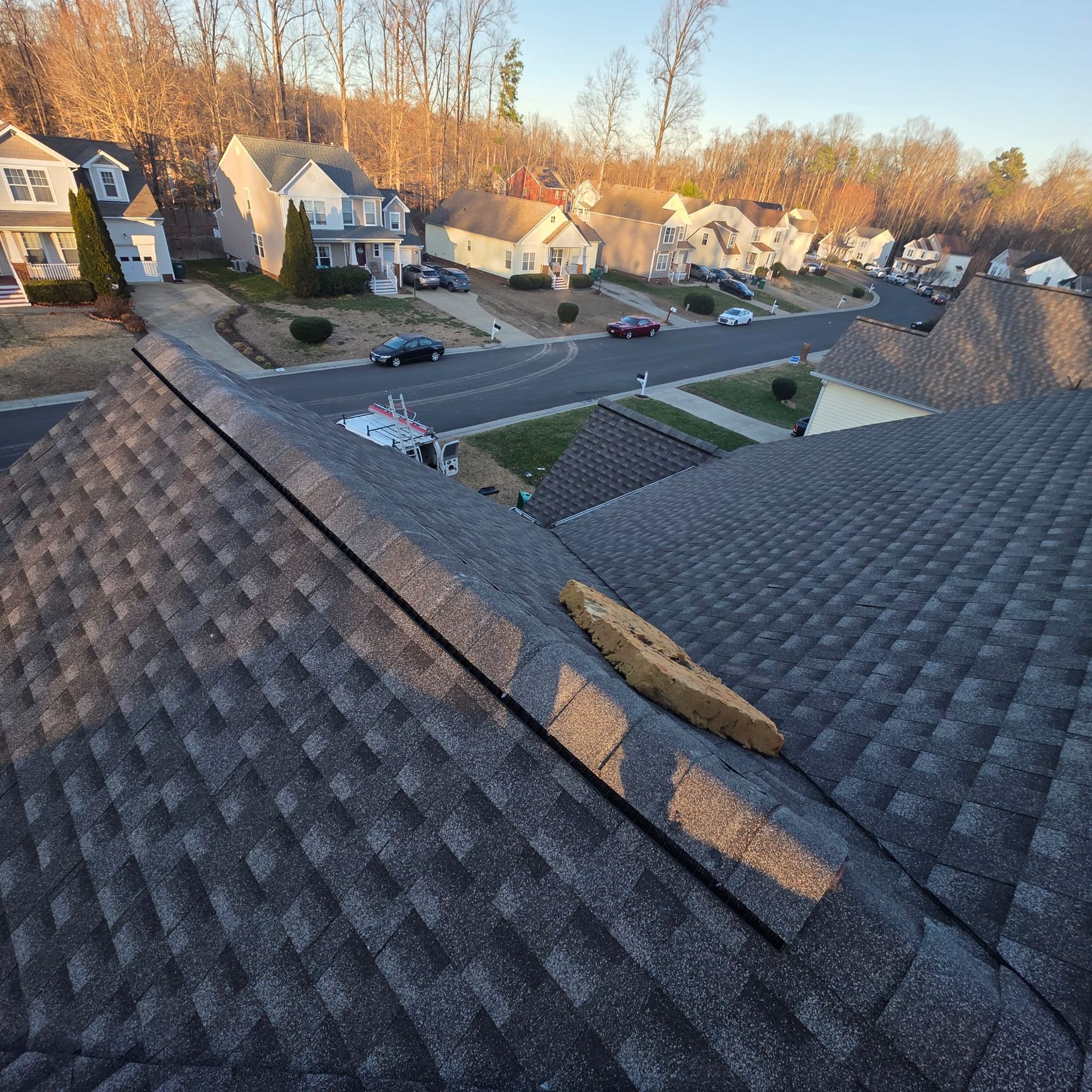 View from a roof, looking at a suburban street with houses and cars.